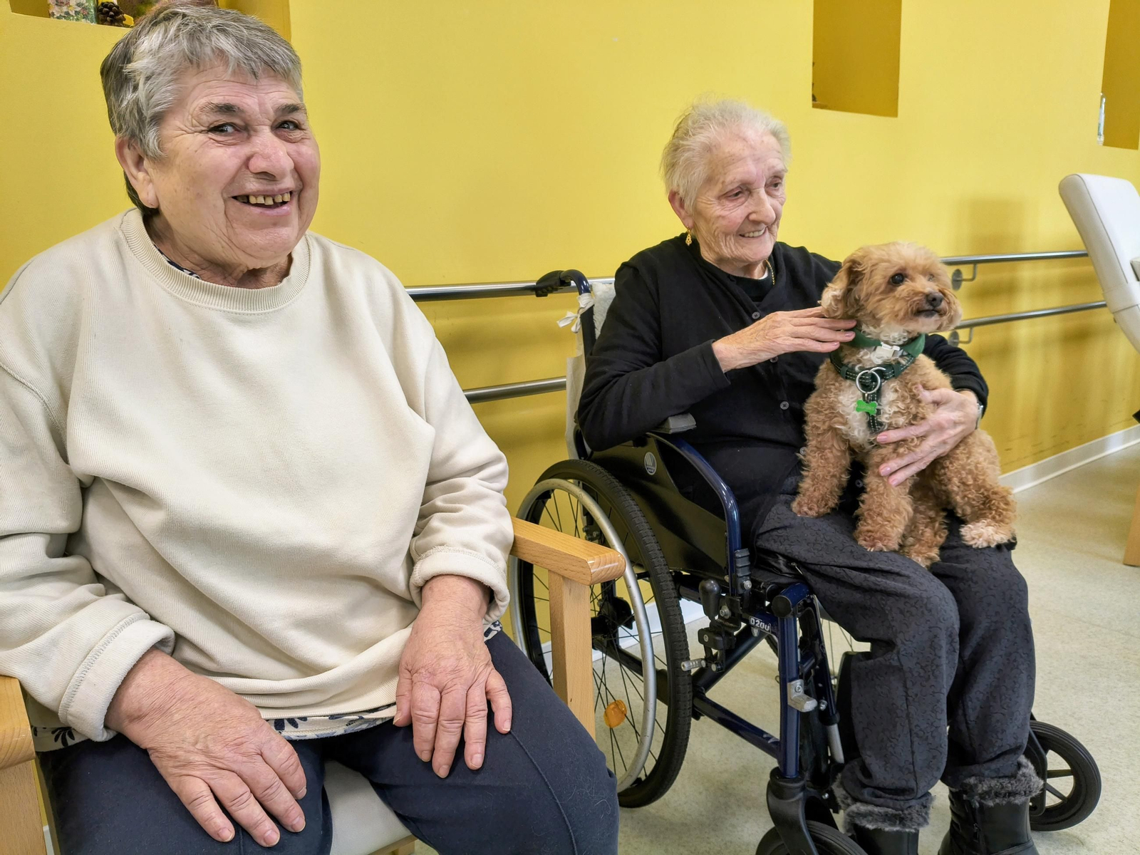 Lola sostiene contenta en brazos a la otra perrita.