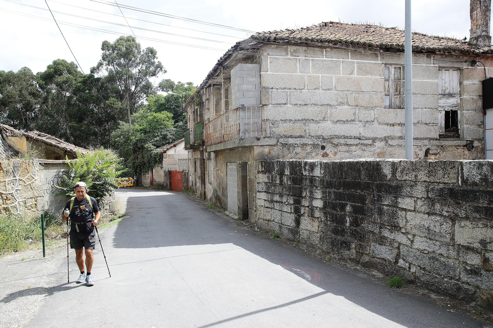 Un peregrino pasa junto a una vivienda okupada en la avenida de Santiago