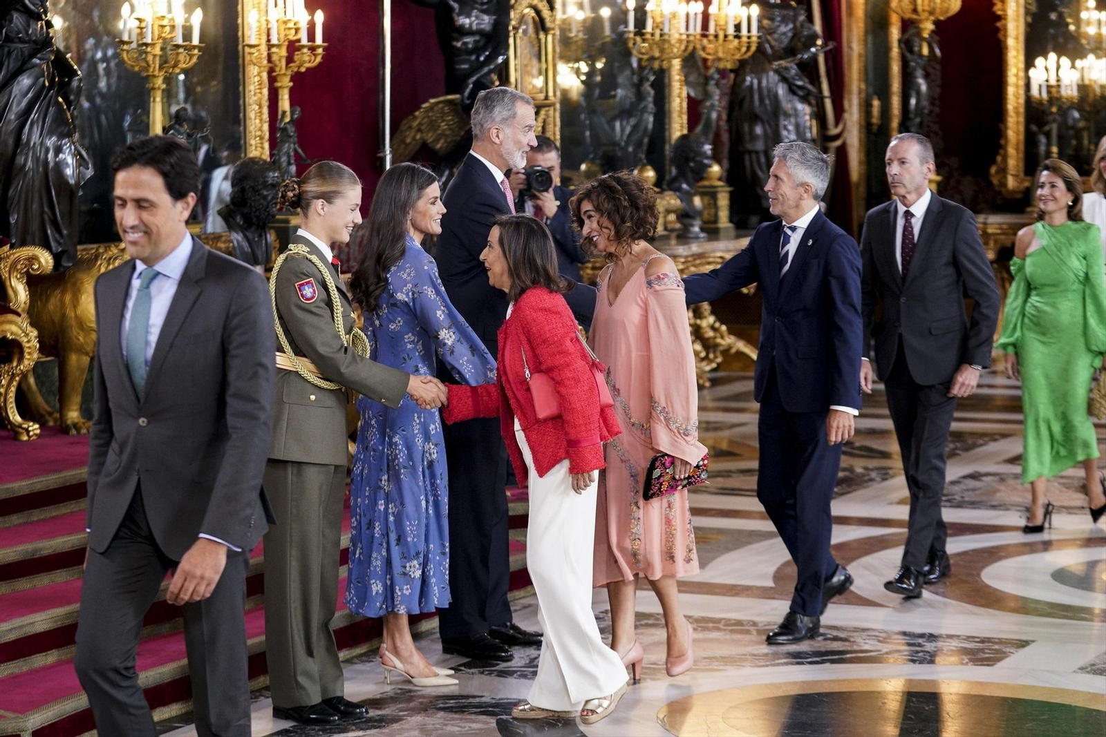 La princesa Leonor (i), la Reina Letizia (2i) y el Rey Felipe VI (c)saludan a la ministra de Defensa en funciones, Margarita Robles (3i), a la ministra de Hacienda y Función Pública en funciones, María Jesús Montero (4d), y el ministro del Interior en funciones, Fernando Grande-Marlaska (3d), a su llegada a una recepción con motivo del Día de la Fiesta Nacional de España.