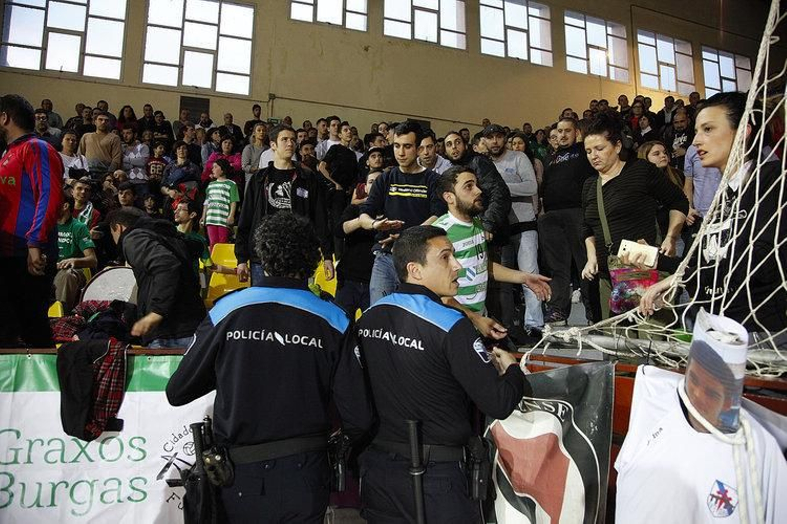 Dos miembros de la Policía Local intentan calmar los ánimos en las gradas de Os Remedios.