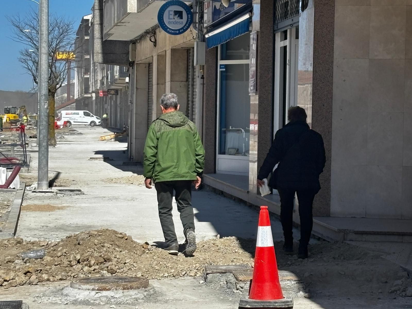 Dos vecinos atravesando los escombros de la obra en el paso peatonal.