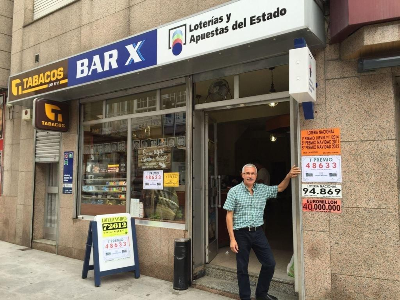 Andrés Martínez a la puerta del BarX, mostrando el número premiado en el sorteo del jueves.