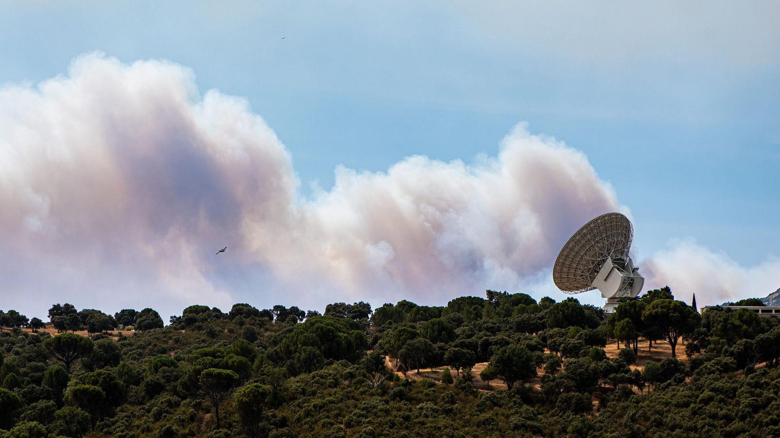 El humo de un fuego cercano sobrevuela una antena de la NASA, a 24 de julio de 2026, en Robledo de Chavela, Madrid
