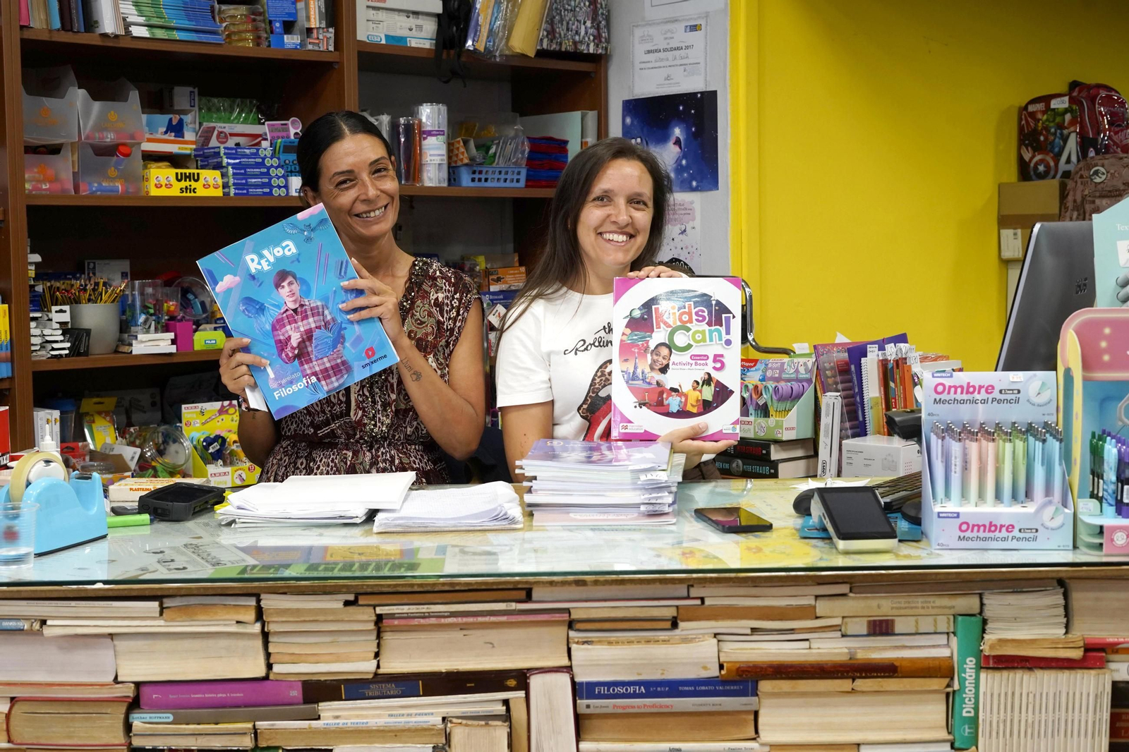 Dos empleadas de la librería La Guía, en Teis, enseñan parte de los libros y material escolar que venden estos días.