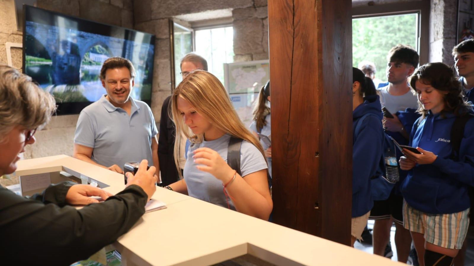 En primer término una de las jóvenes del exterior mientras le sellan la Compostela