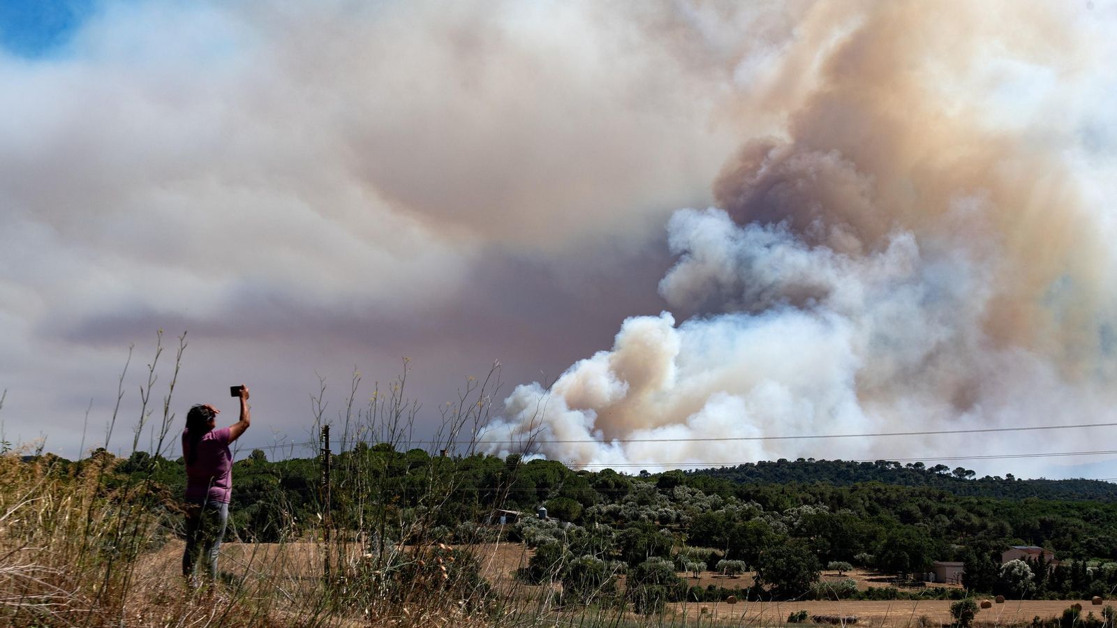 Una persona le hace una foto al humo del incendio, en La Bisbal d'Empordà.
