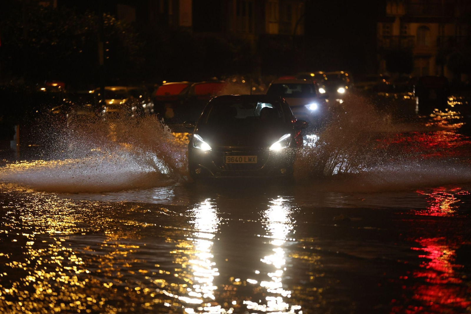 Un coche circula por una carretera anegada.