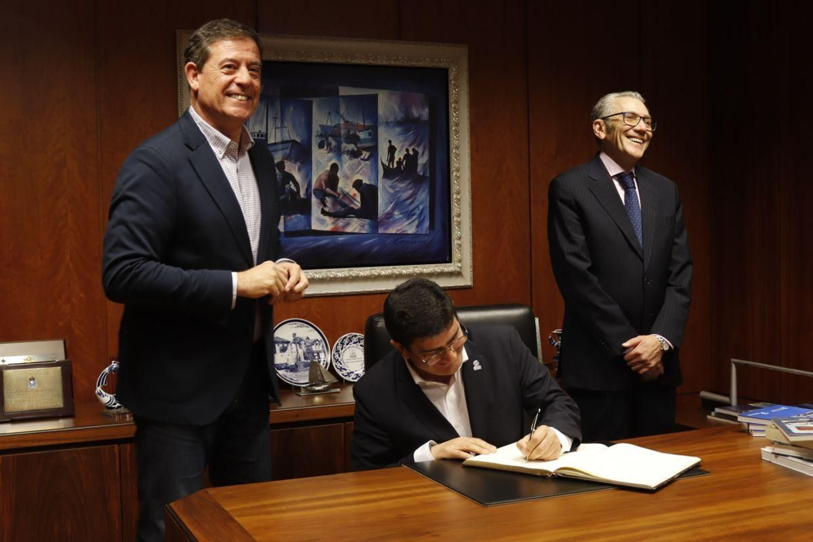 Xosé Ramón Gómez Besteiro y Javier Touza en la sede de ARVI, con Pedro Blanco firmando el libro de visitantes.