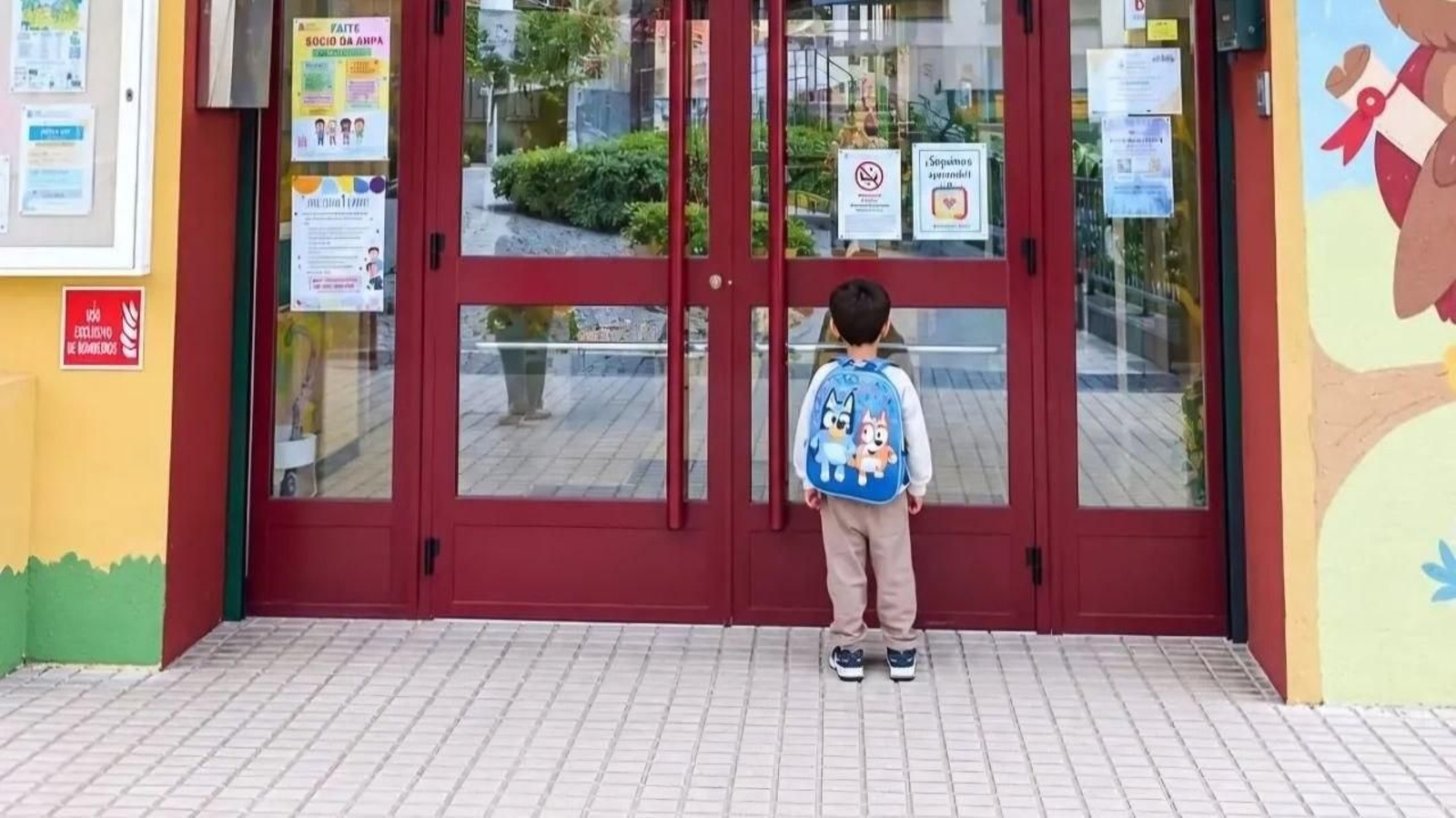 El niño esperando frente a la puerta de la escuela infantil Vila Laura.