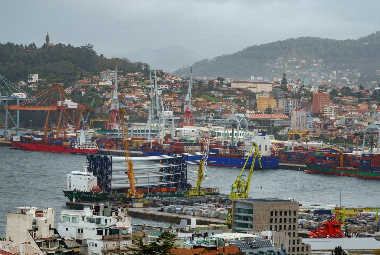 Carga de grandes piezas eólicas en el puerto de Vigo con el muelle de contenedores al fondo.