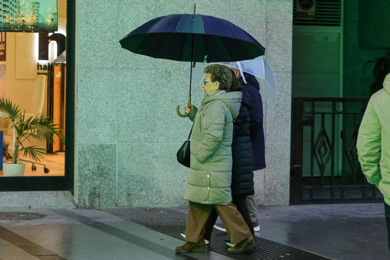 res transeúntes ayer por las calles de Vigo, ataviados con abrigo y paraguas.