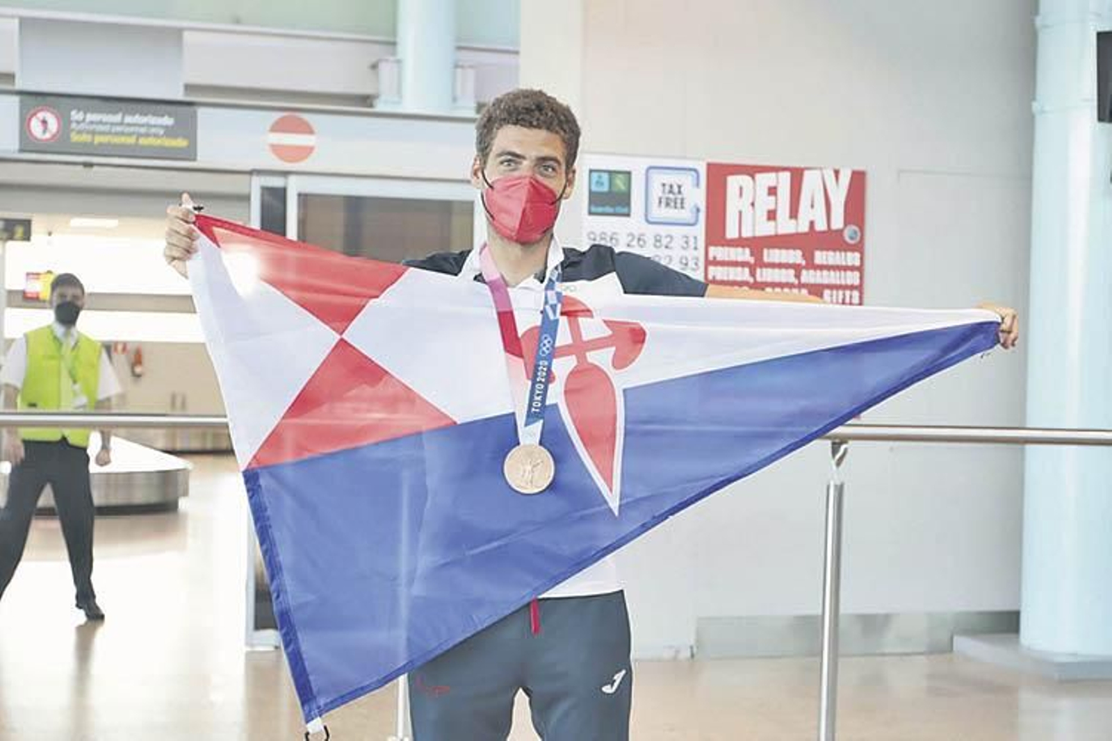Nico Rodríguez posa con la bandera del Náutico de Vigo y la medalla nada más aterrizar. (DAVID FERNÁNDEZ)