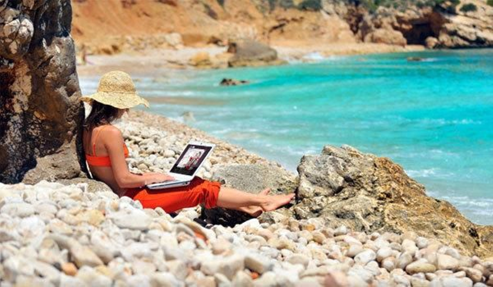 Una mujer con un ordenador en una playa.