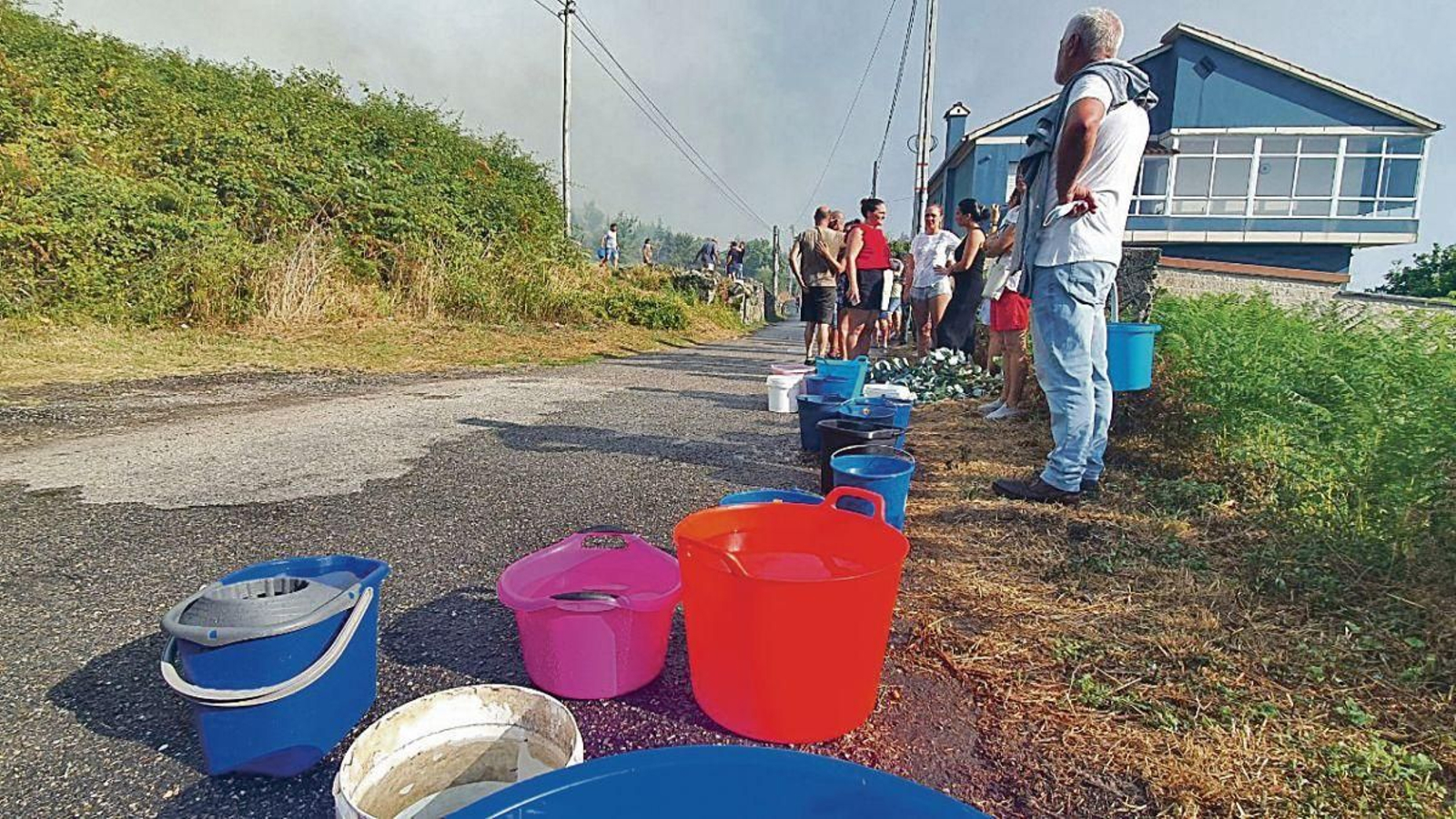 Los vecinos, con cubos y otros recipientes llenos de agua para hacer frente al fuego.