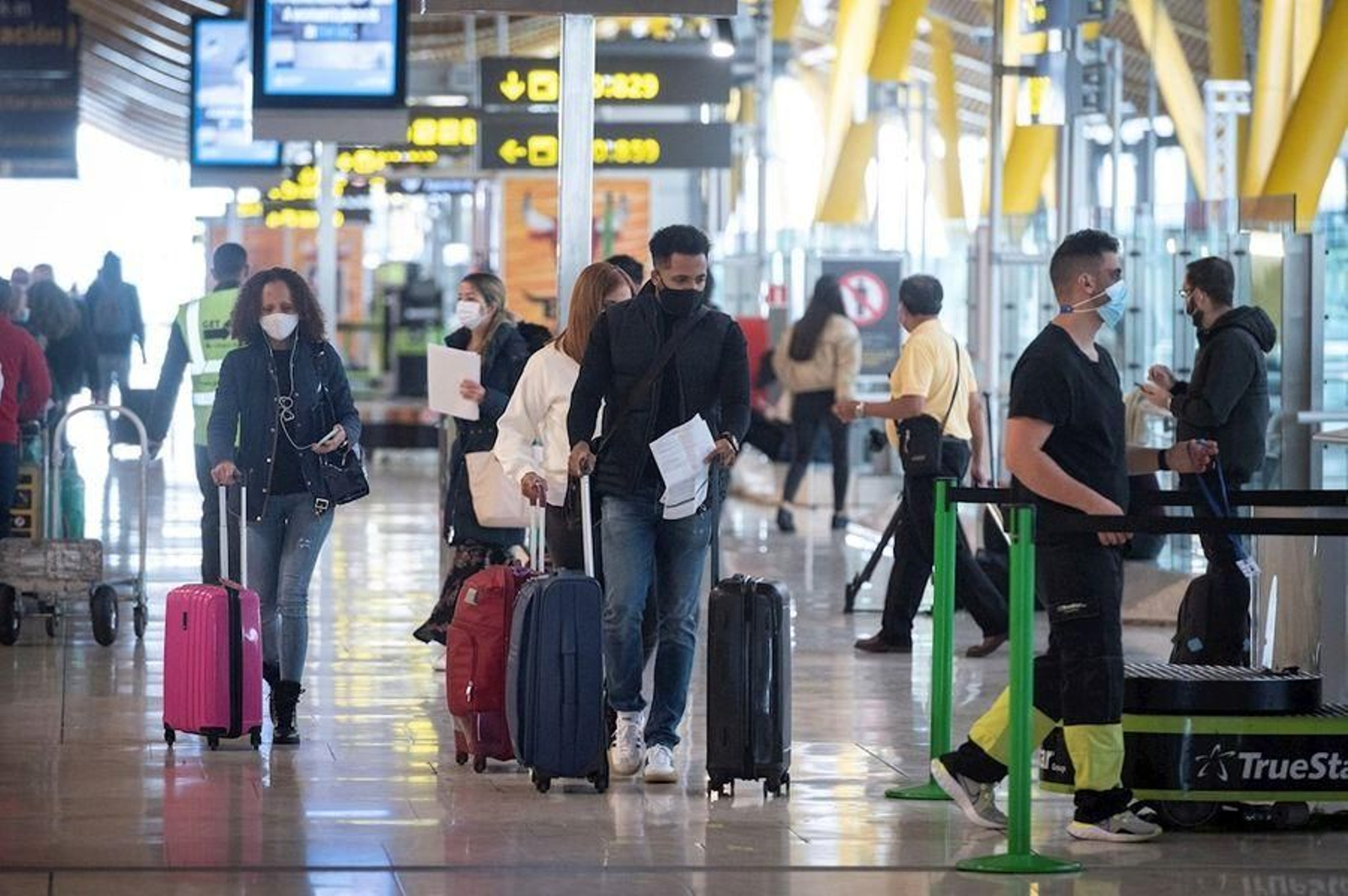Grupos de viajeros con  mascarilla en el aeropuerto de Barajas.