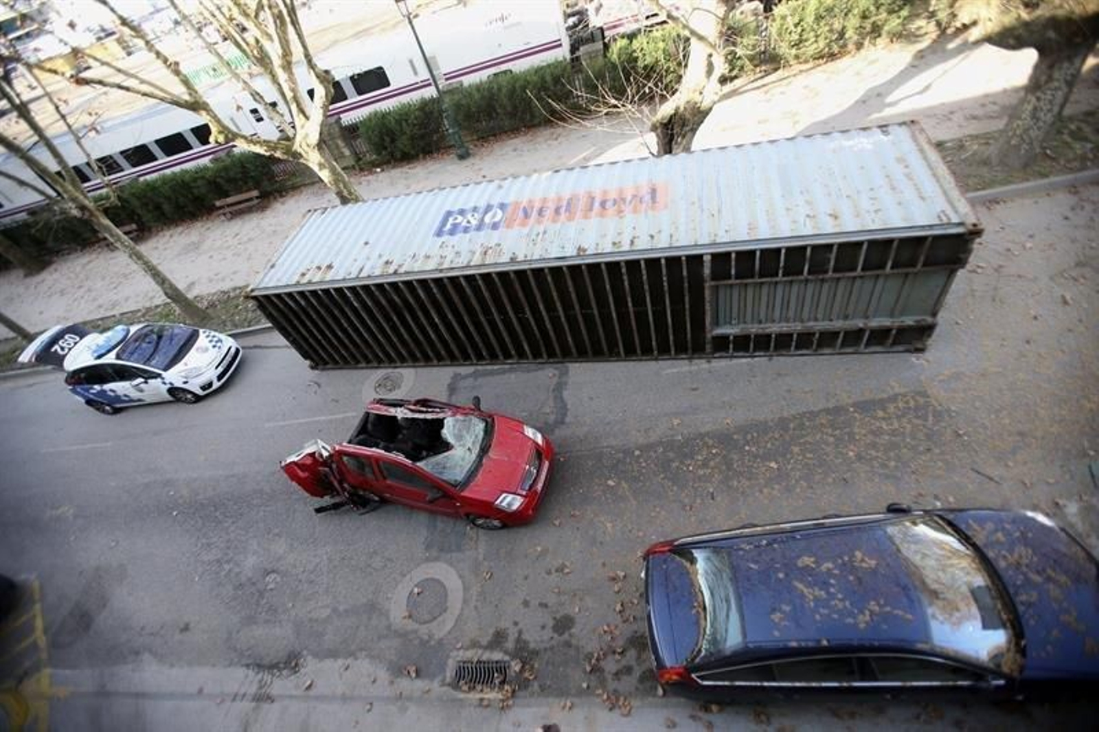 El coche destrozado y el contenedor caído.