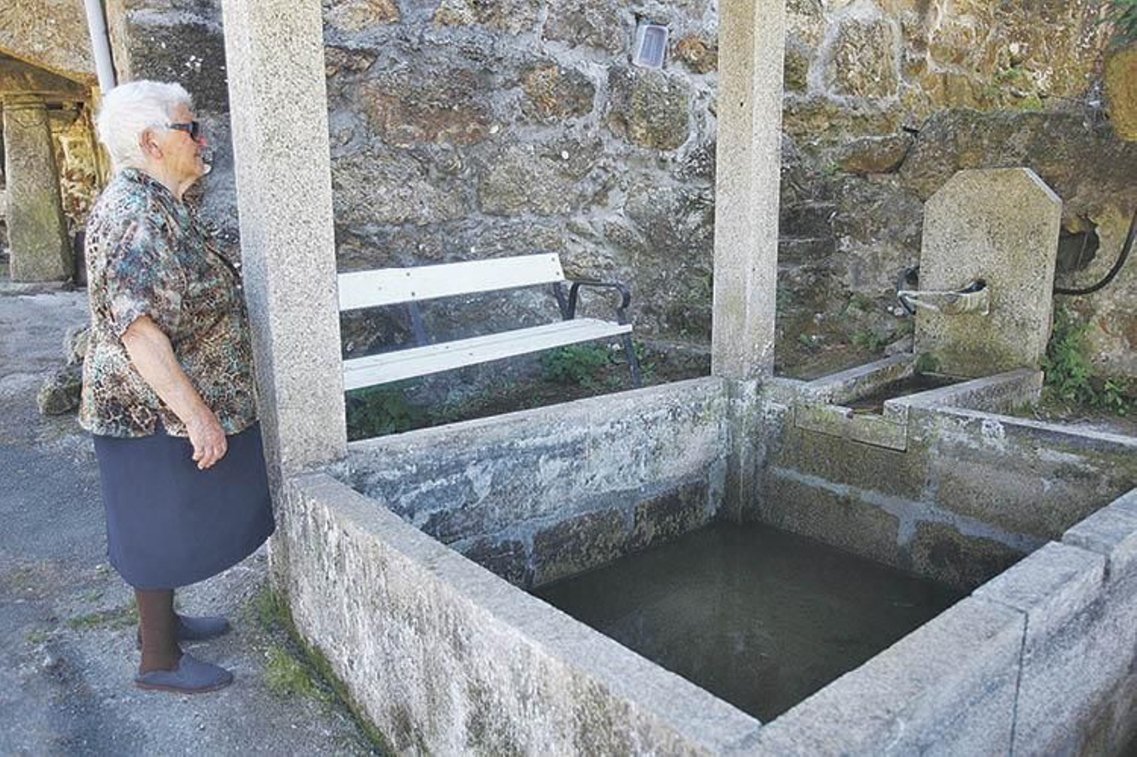 Ascensión Díaz observa a única fonte que abastece a Agrelo, da que non mana ni unha pinga.