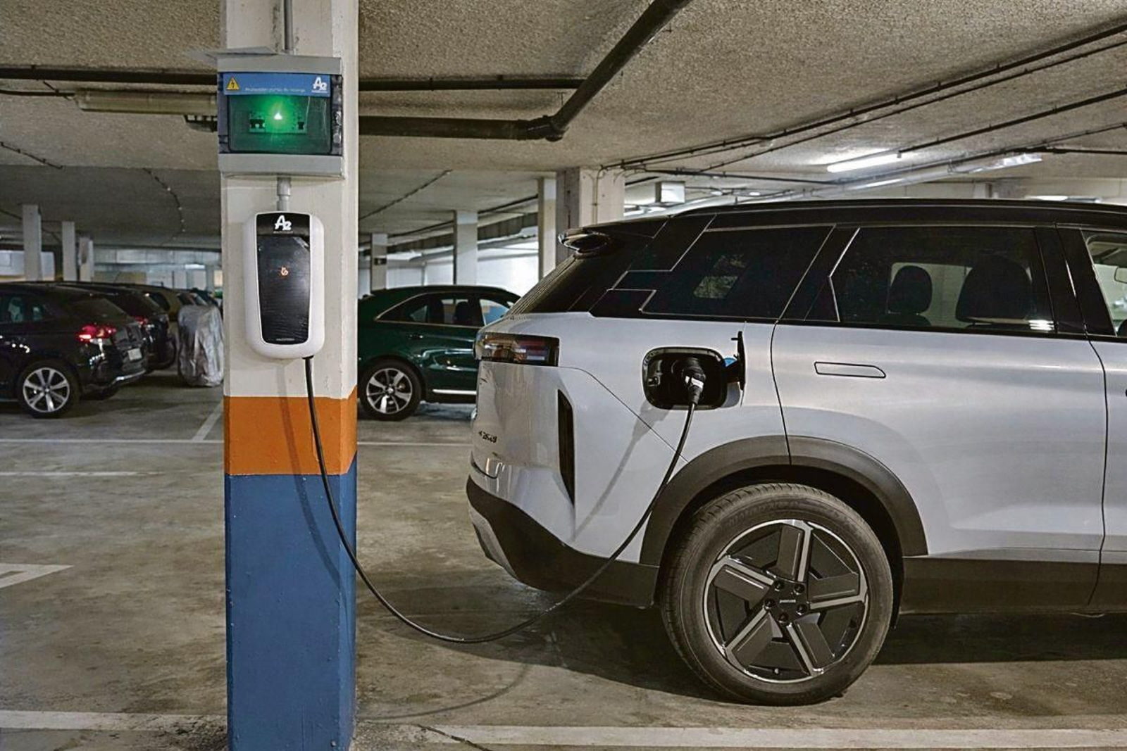 Un coche eléctrico llena su batería en un punto de carga localizado en un aparcamiento.