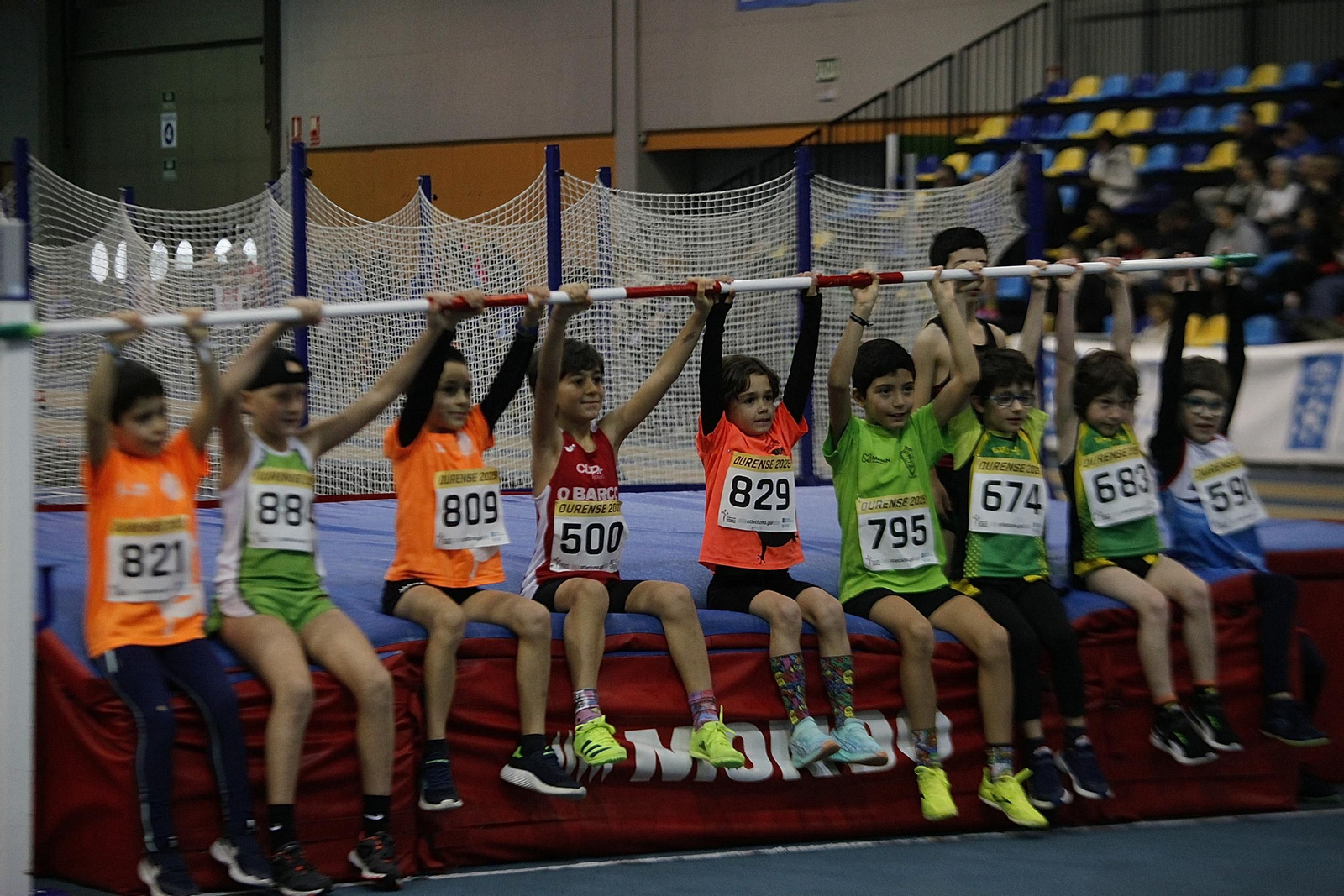 Los participantes de la prueba de salto de altura de la categoría sub-10 posan para una foto de familia con el listón por encima de sus cabezas.