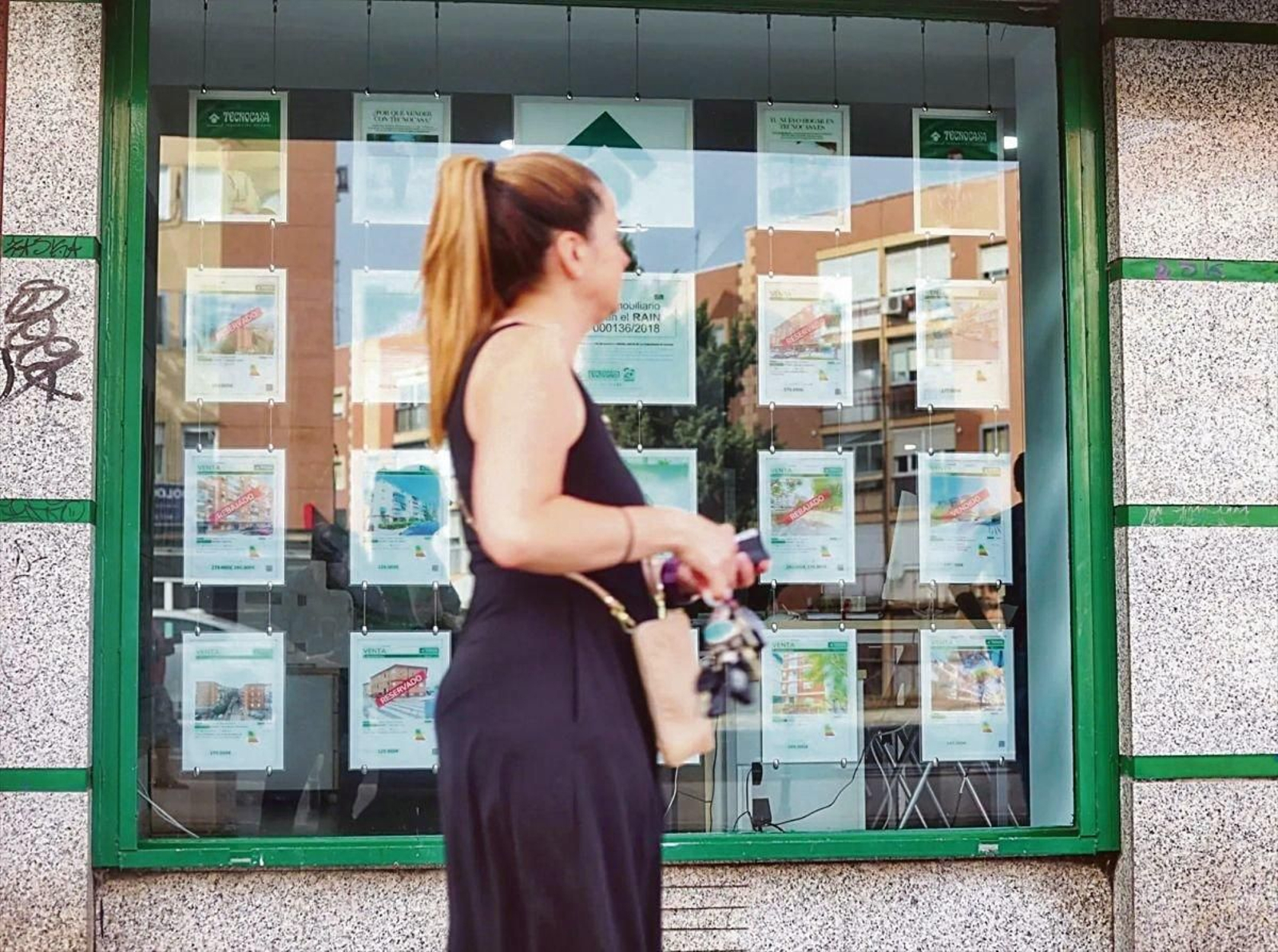 Una joven pasa ante el escaparate de una agencia de alquiler de pisos.