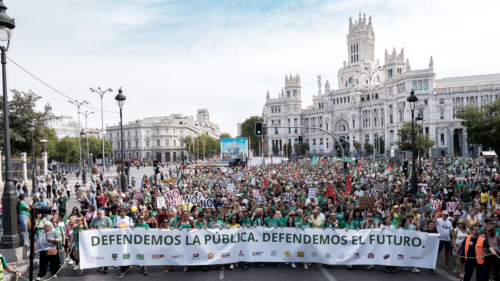 Numerosas personas sostienen pancarta con lema 'Defendemos la pública. Defendemos el futuro'.