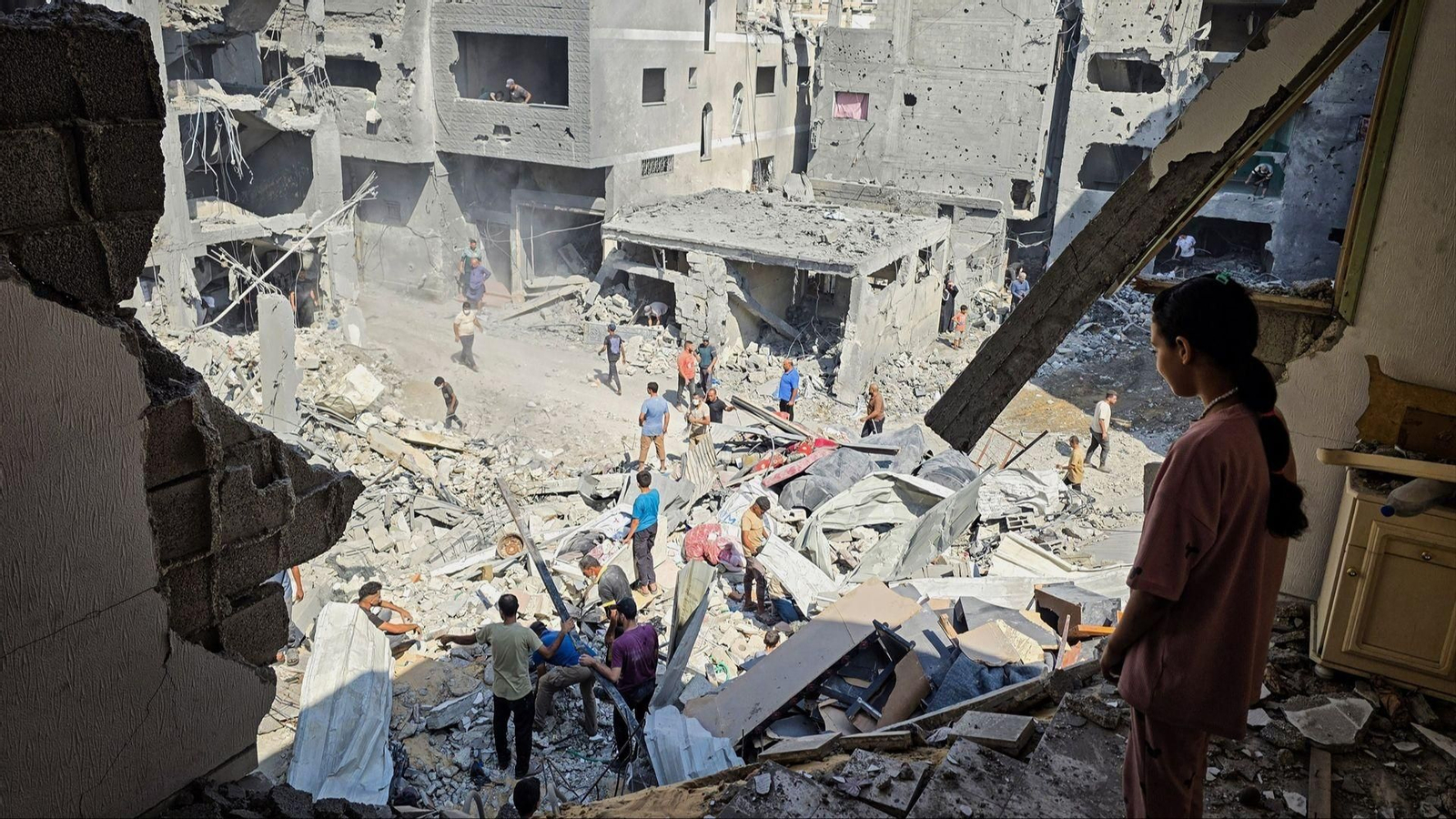 Varios palestinos entre las ruinas después de que un ataque aéreo israelí destruyera sus casas.