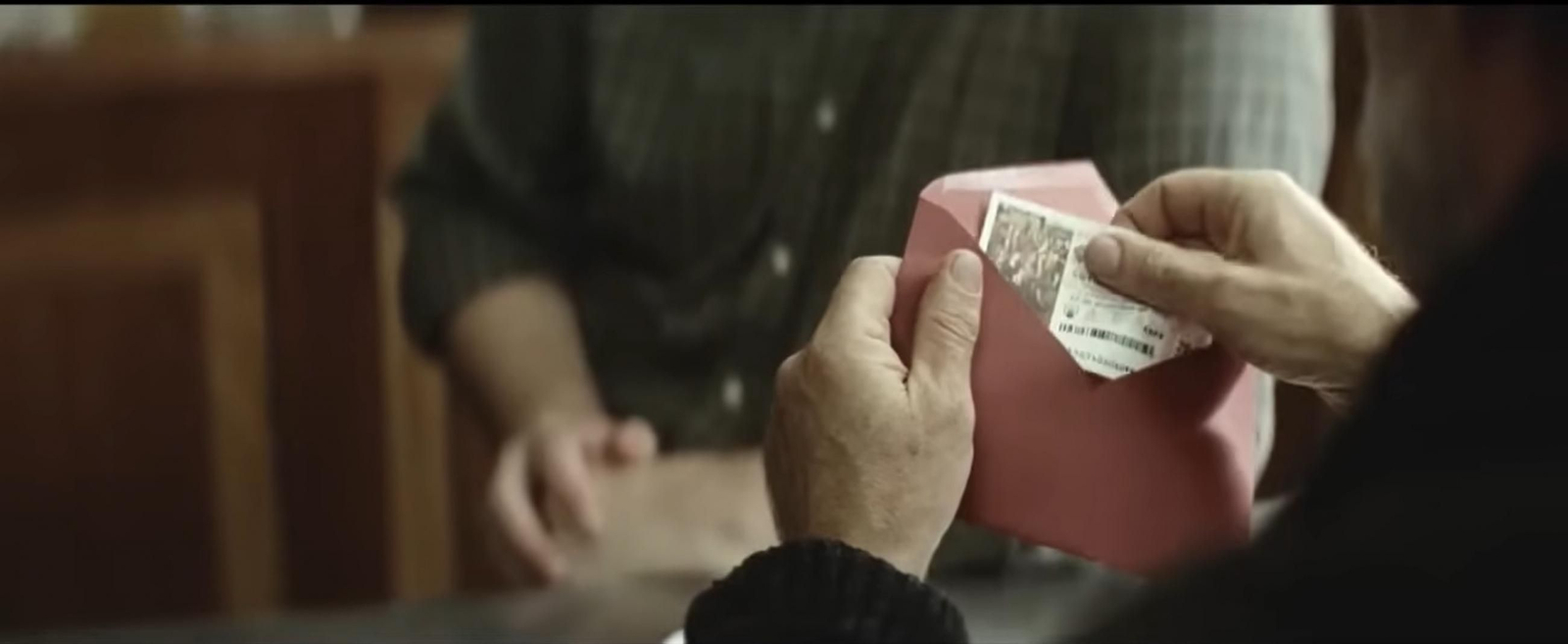 Fotograma del anuncio de la Lotería del año 2014 en el que se puede ver al protagonista recibiendo el boleto que le habían guardado.