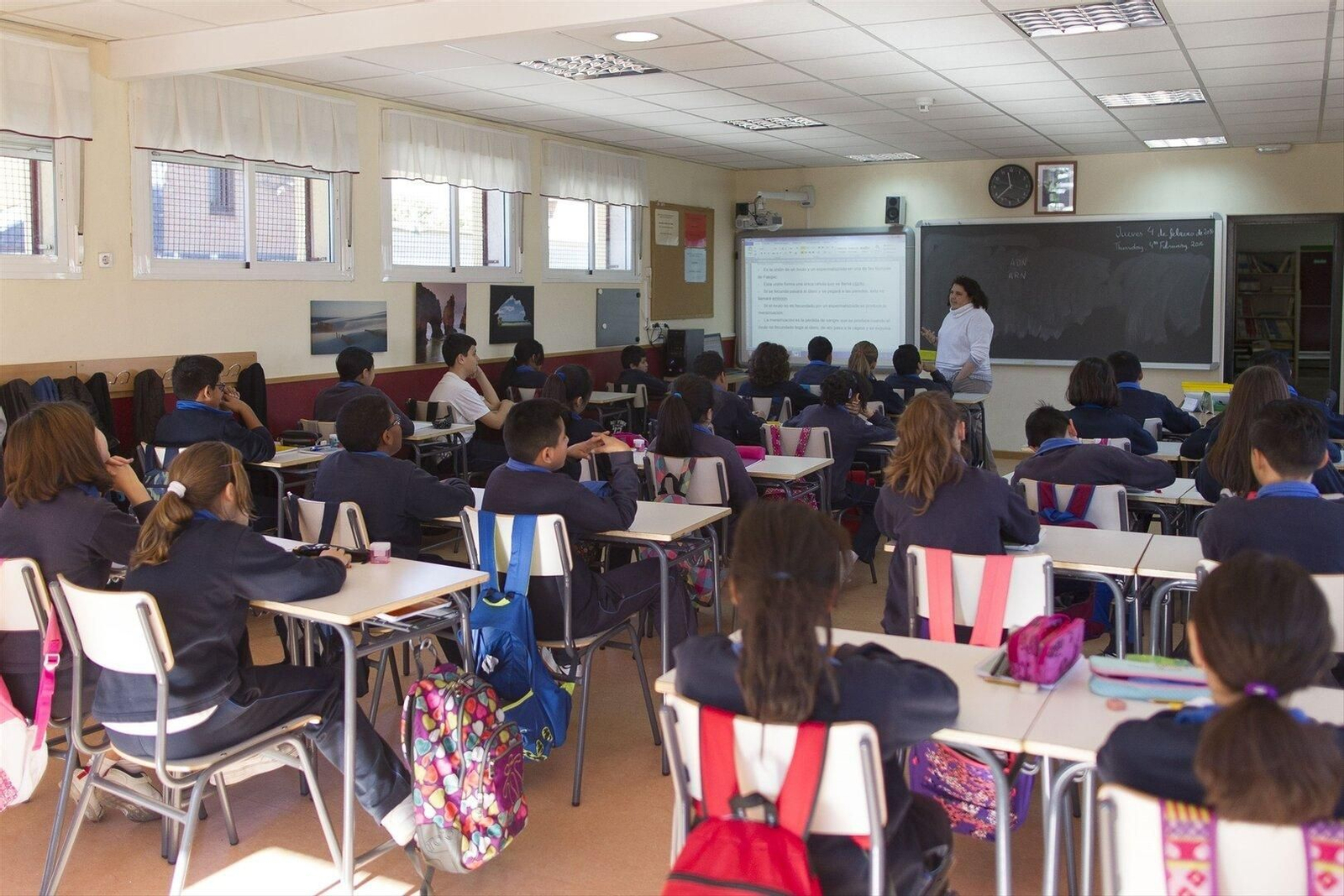 Niños en clase atendiendo a la profesora.