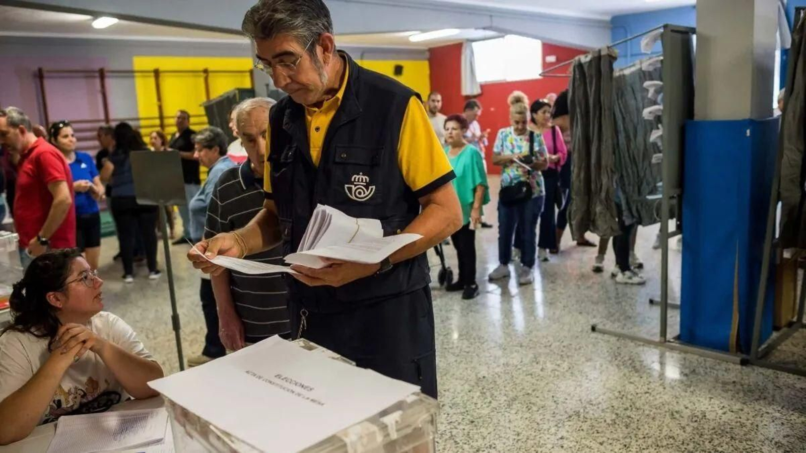Un cartero entrega en una mesa el voto por correo.
