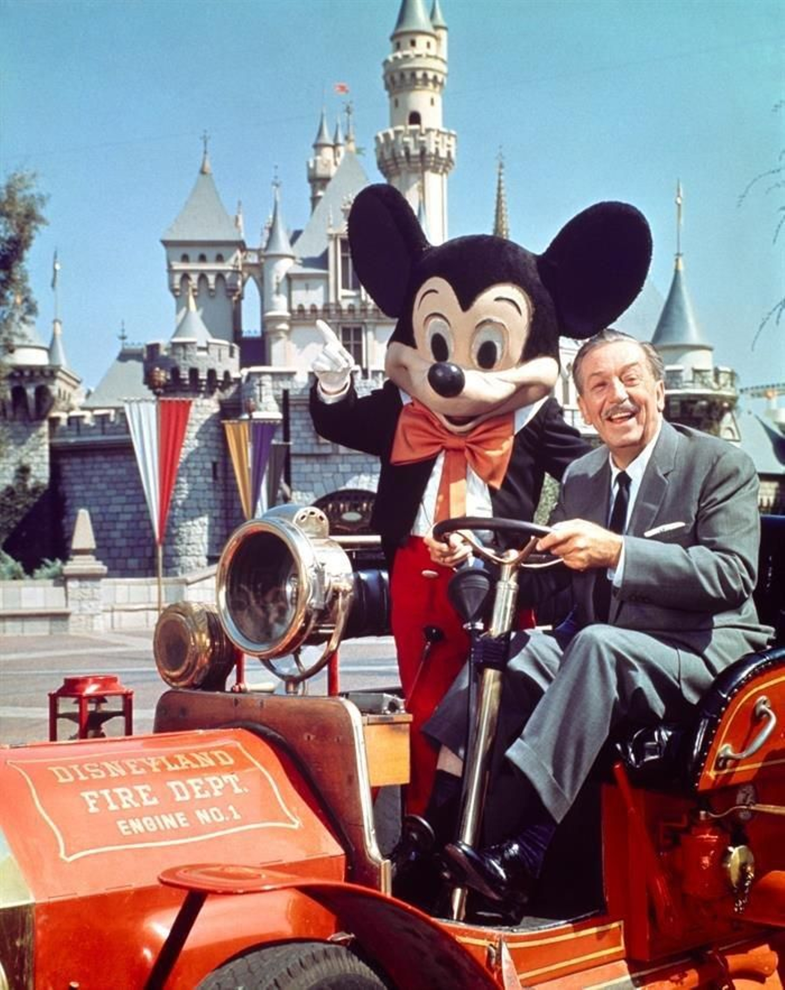 Walter Elias Disney, conocido por Walt Disney, mientras conduce un camión de bomberos junto a su personaje más famoso, Mickey Mouse