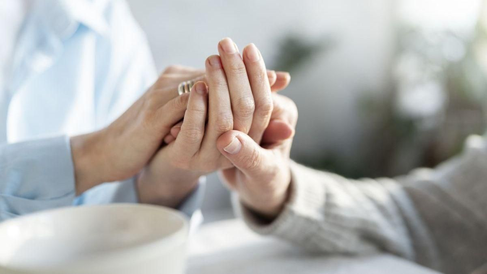 Una persona sostiene la mano de una paciente con párkinson.