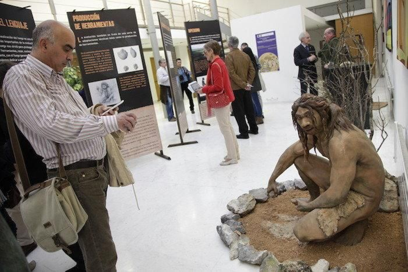 Visitantes de la exposición pasan ante una de las iguras de la muestra.