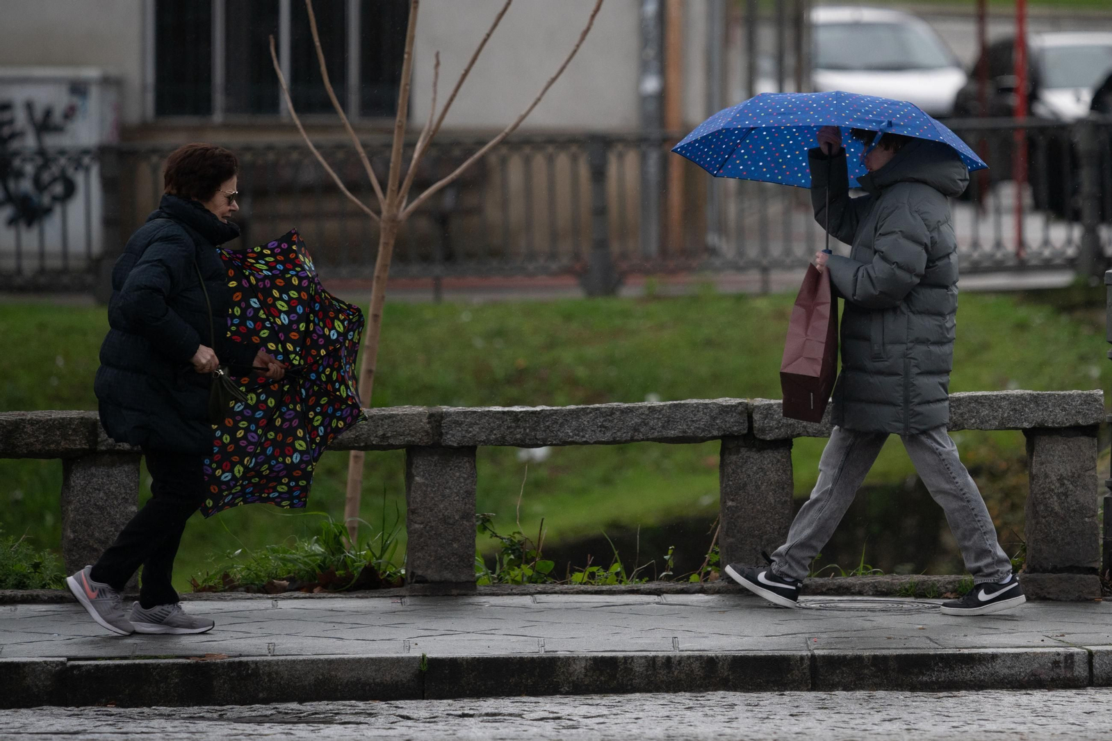 Una mujer evita que el viento se lleve su paraguas.