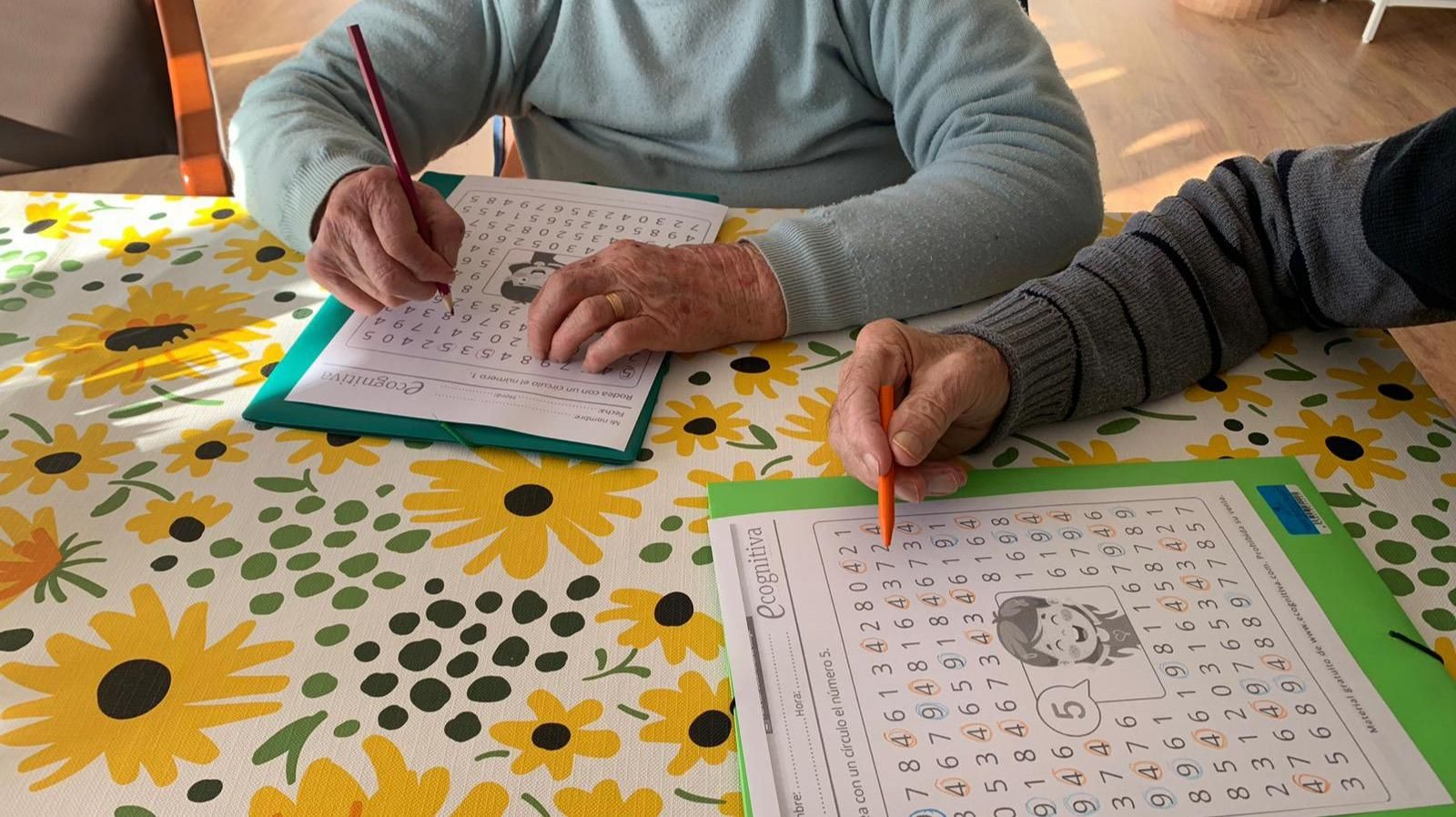 Dos usuarios de una casa do maior realizan ejercicios cognitivos y de entretenimiento.