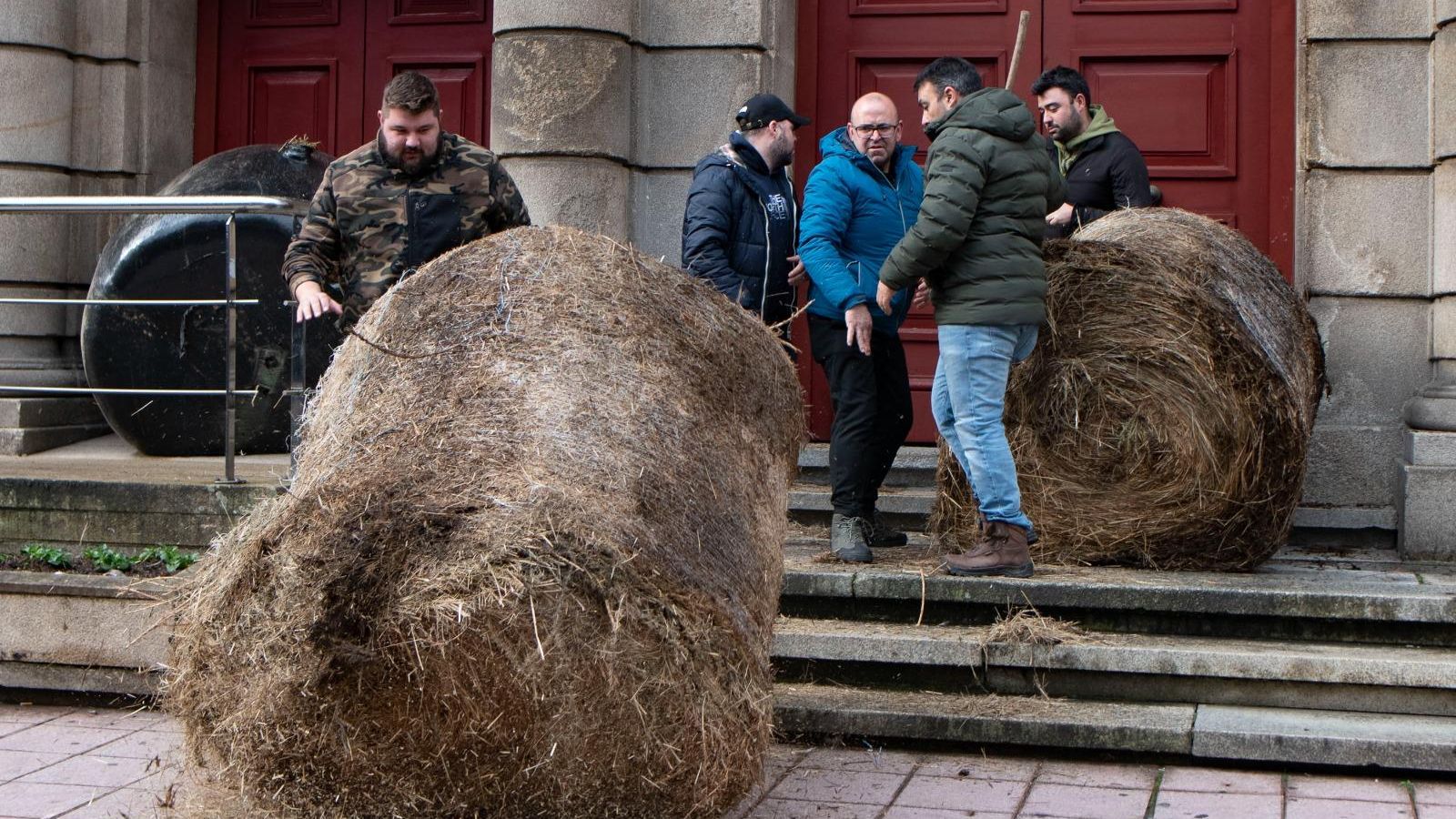 Momento en el que los agricultores y ganaderos acceden a retirar el tractor en la puerta de la Subdelegación, así como los rollos de paja.