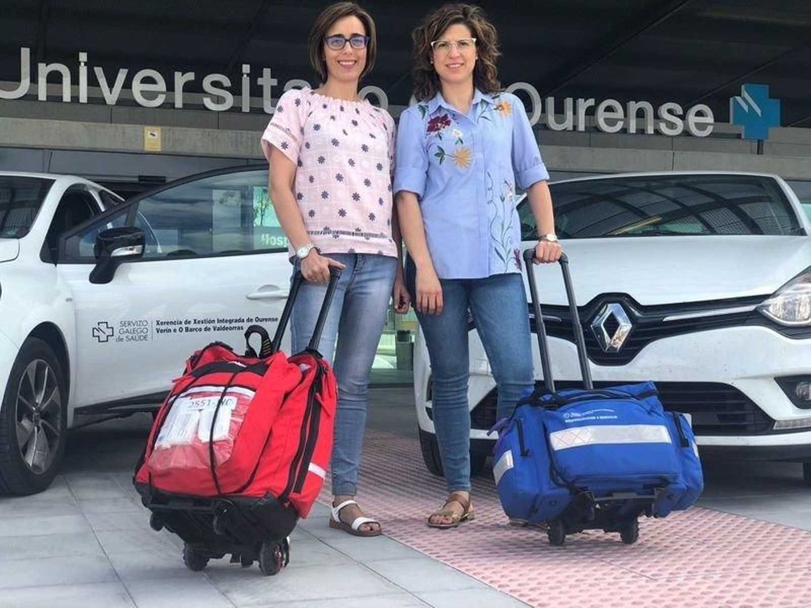 Ana Fernández Conde, enfermera, y Nancy Marra, supervisora de HADO, frente a los coches de la flota de la unidad.