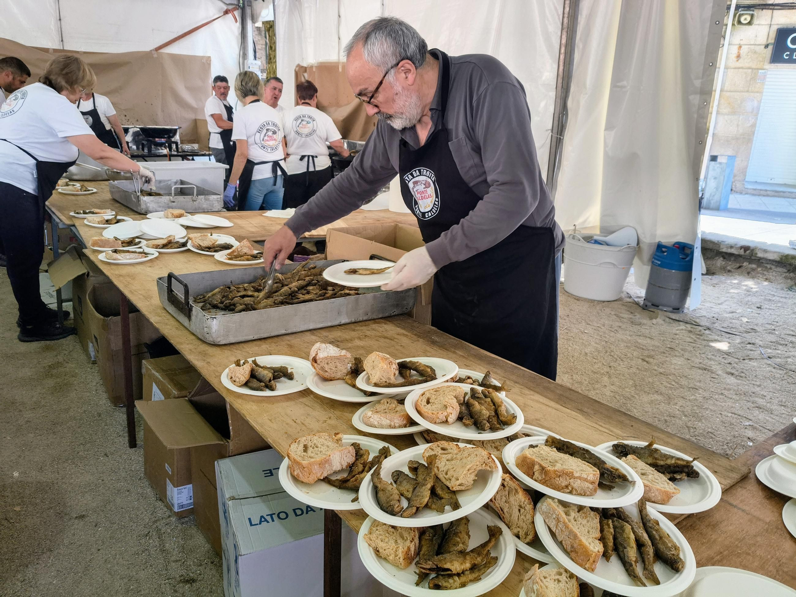 Voluntarios cocinando y repartiendo las raciones de truchas en La Alameda.
