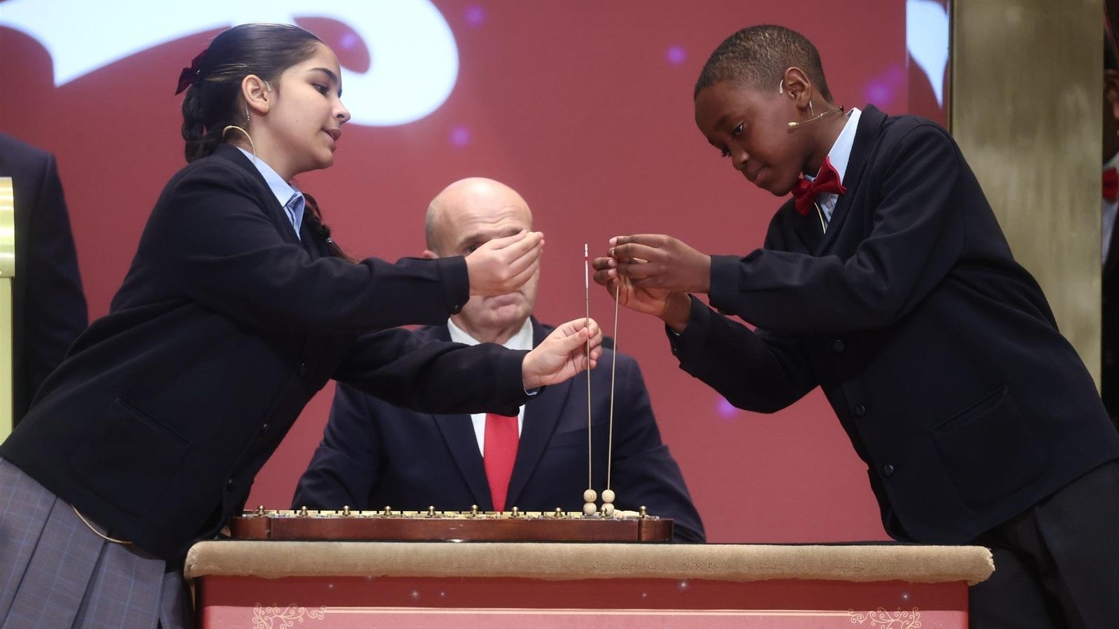 El niño y niña de San Ildefonso colocan en los alambres las bolas con los números premiados.