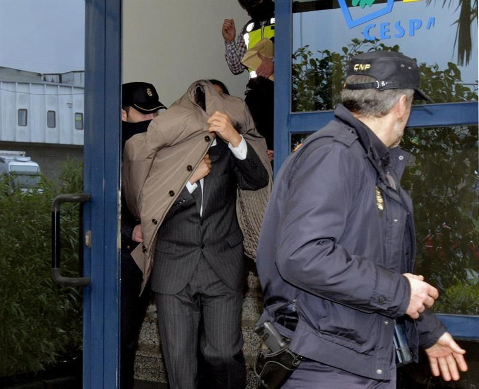 Agentes de la Policía salen con una persona esta mañana de la sede de la empresa Cespa en Santiago de Compostela que han registrado dentro de la Operación Patos