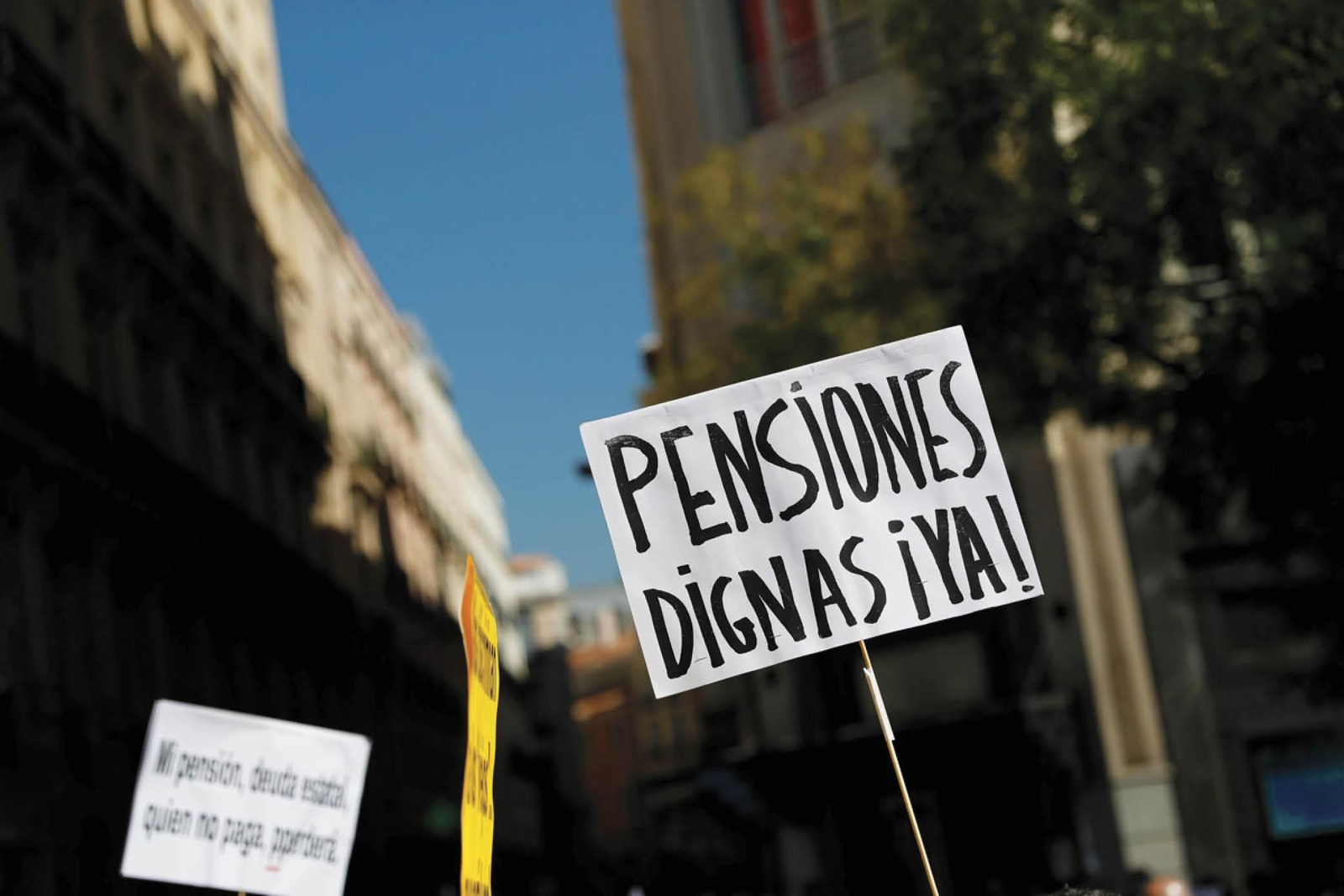 Una persona sostiene una pancarta en contra del actual sistema de pensiones durante una manifestación.