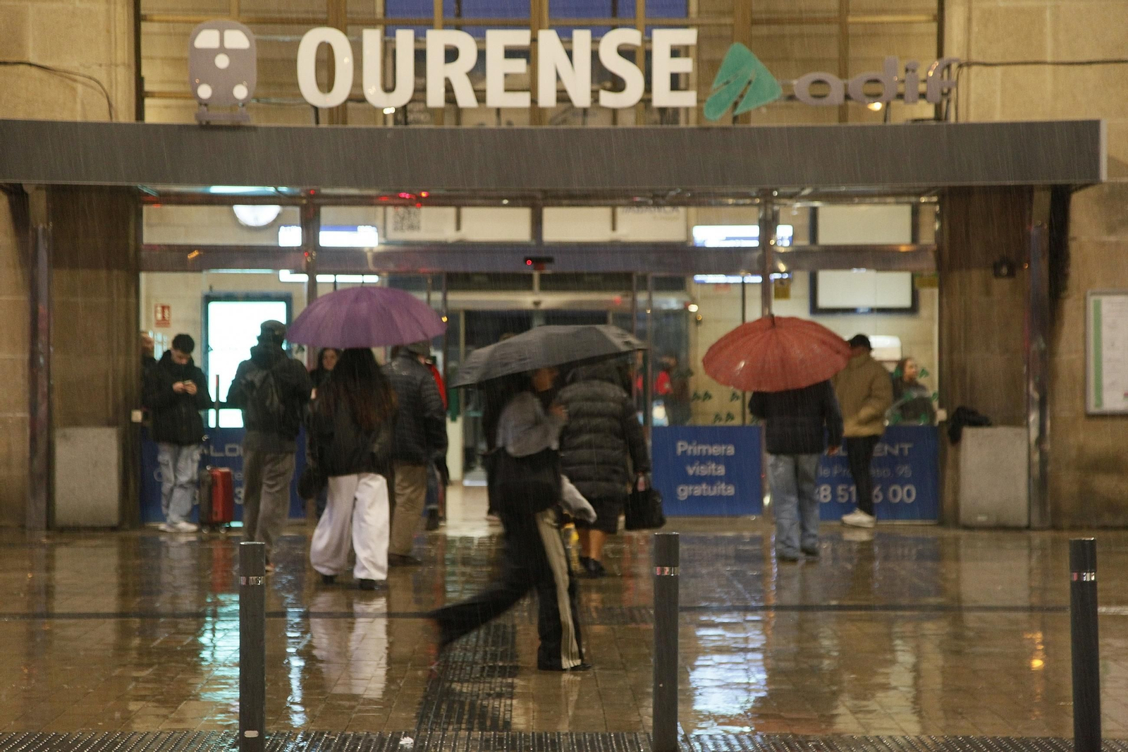 Los viajeros se protegen de la lluvia a su llegada a Ourense.