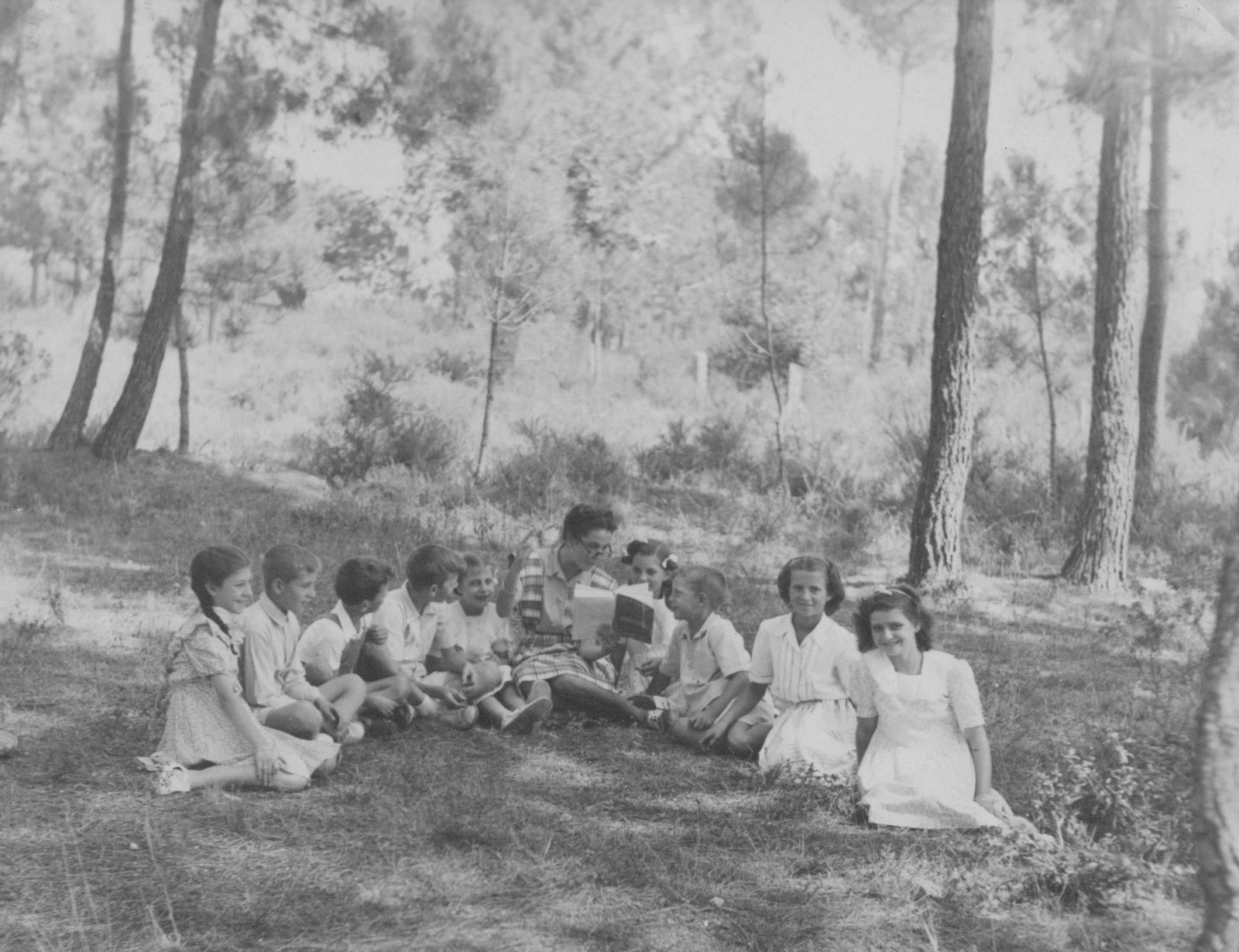 Carmiña no Campo de Roma en San Lourenzo de Piñor, ca. 1945, lendo e facendo de cicerone a un grupo de primos e amigos.