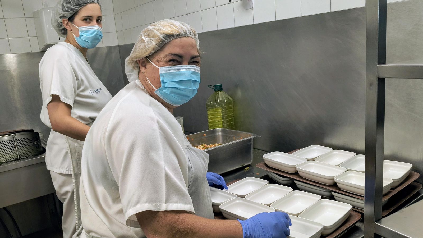 Una cocinera y pinche emplatan las ensaladas de legumbres.