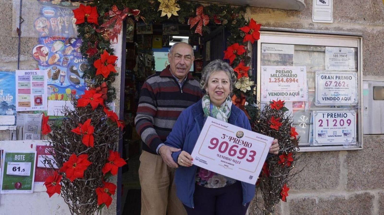 Quique y Merchi, en el exterior de su kiosco con el cartel premiado.