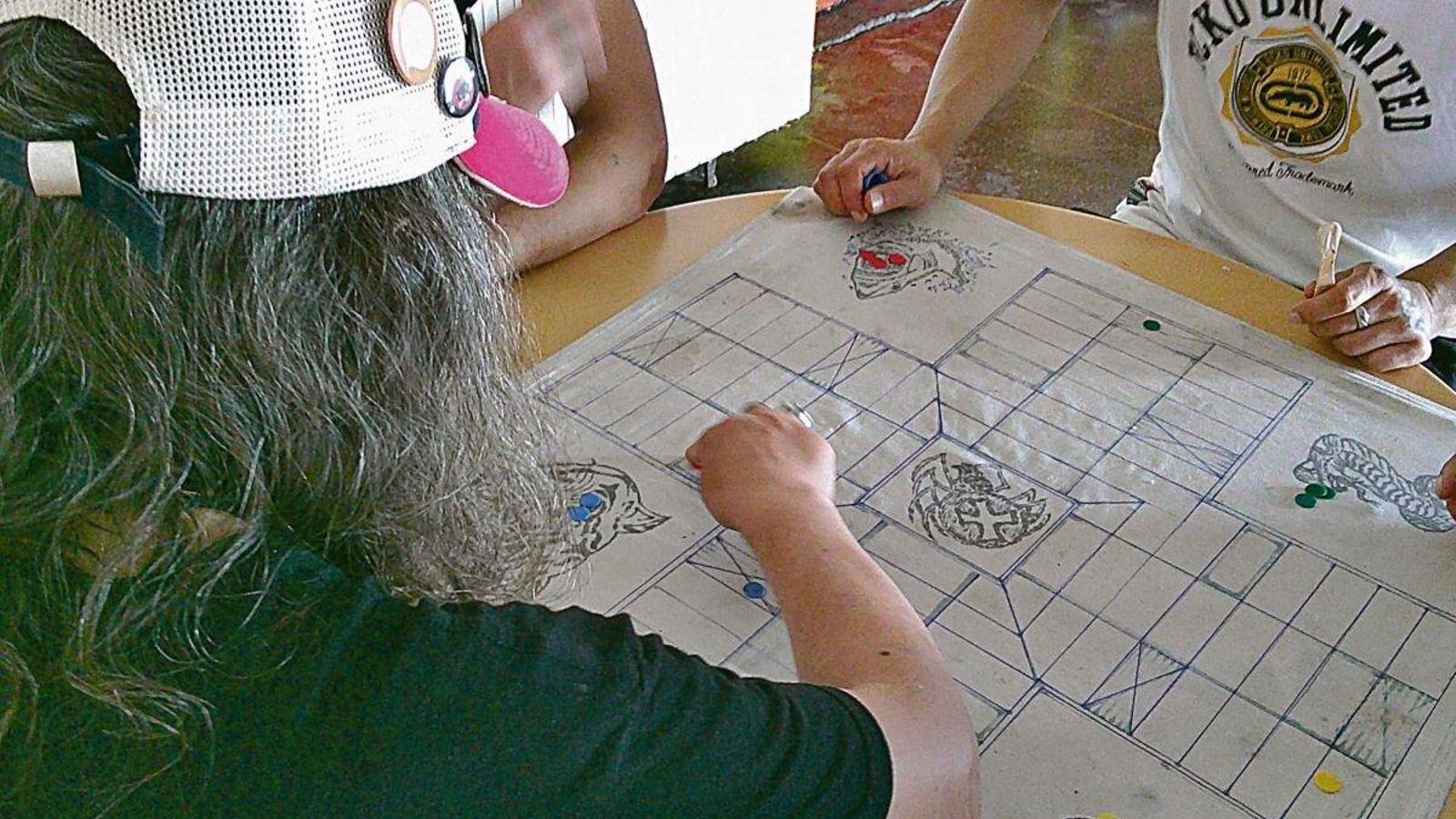 Un grupo de internos juega al parchís sobre un tablero de tela.