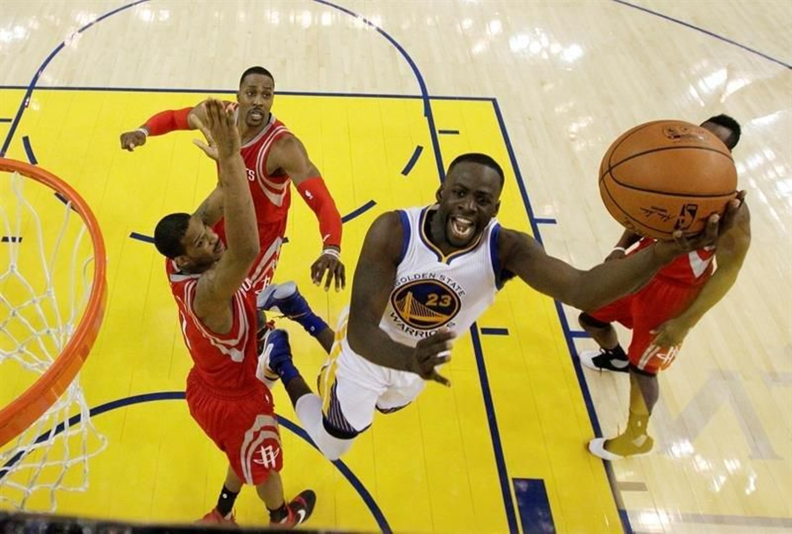 El jugador de los Warriors de Golden State Draymond Green (c) entra a canasta ante varios jugadores de los Rockets de Houston.