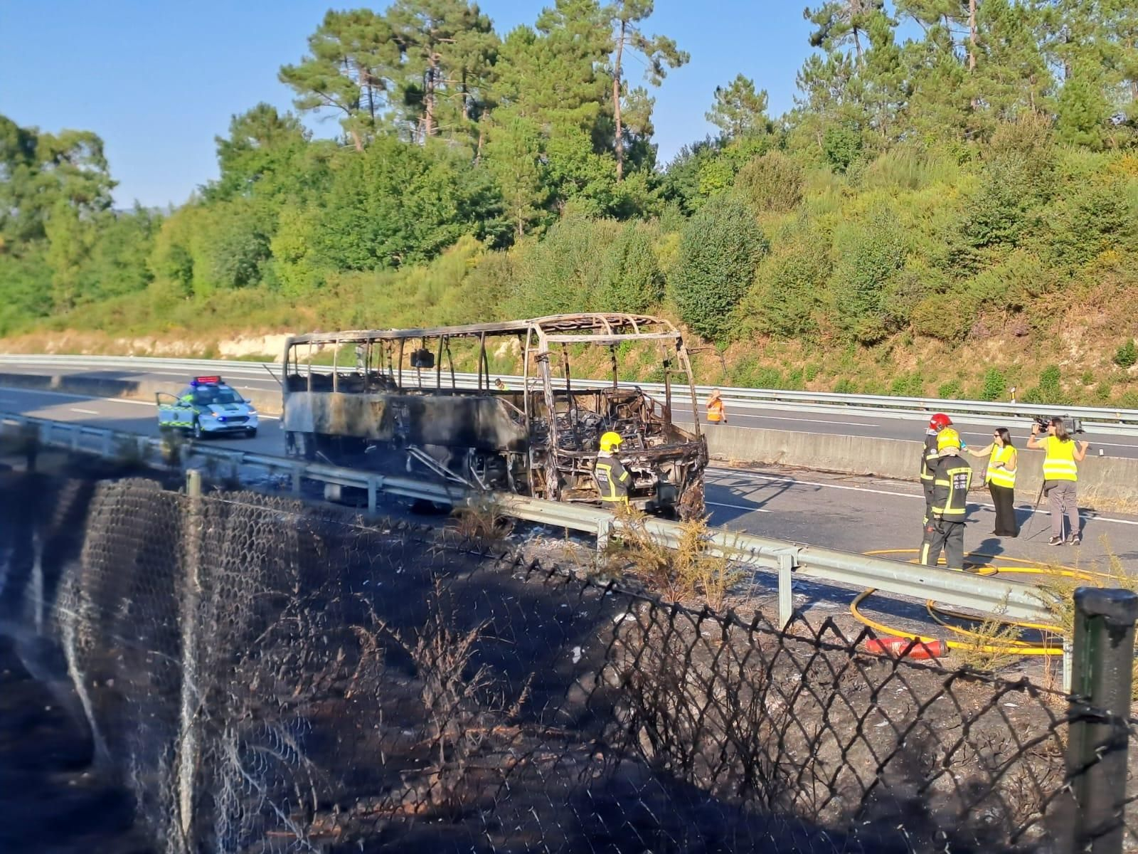 Los servicios de emergencia trabajan en la extinción del incendio del autobús y de la vegetación próxima.