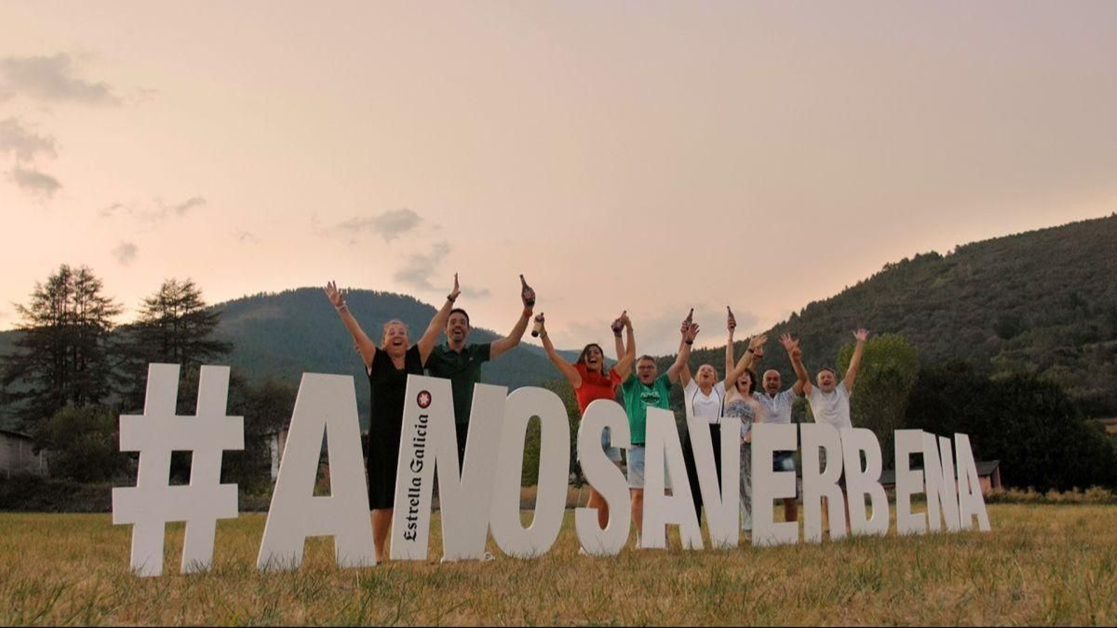 Los organizadores de A Nosa Verbena posa con el cartel del evento en Santiago de Compostela.