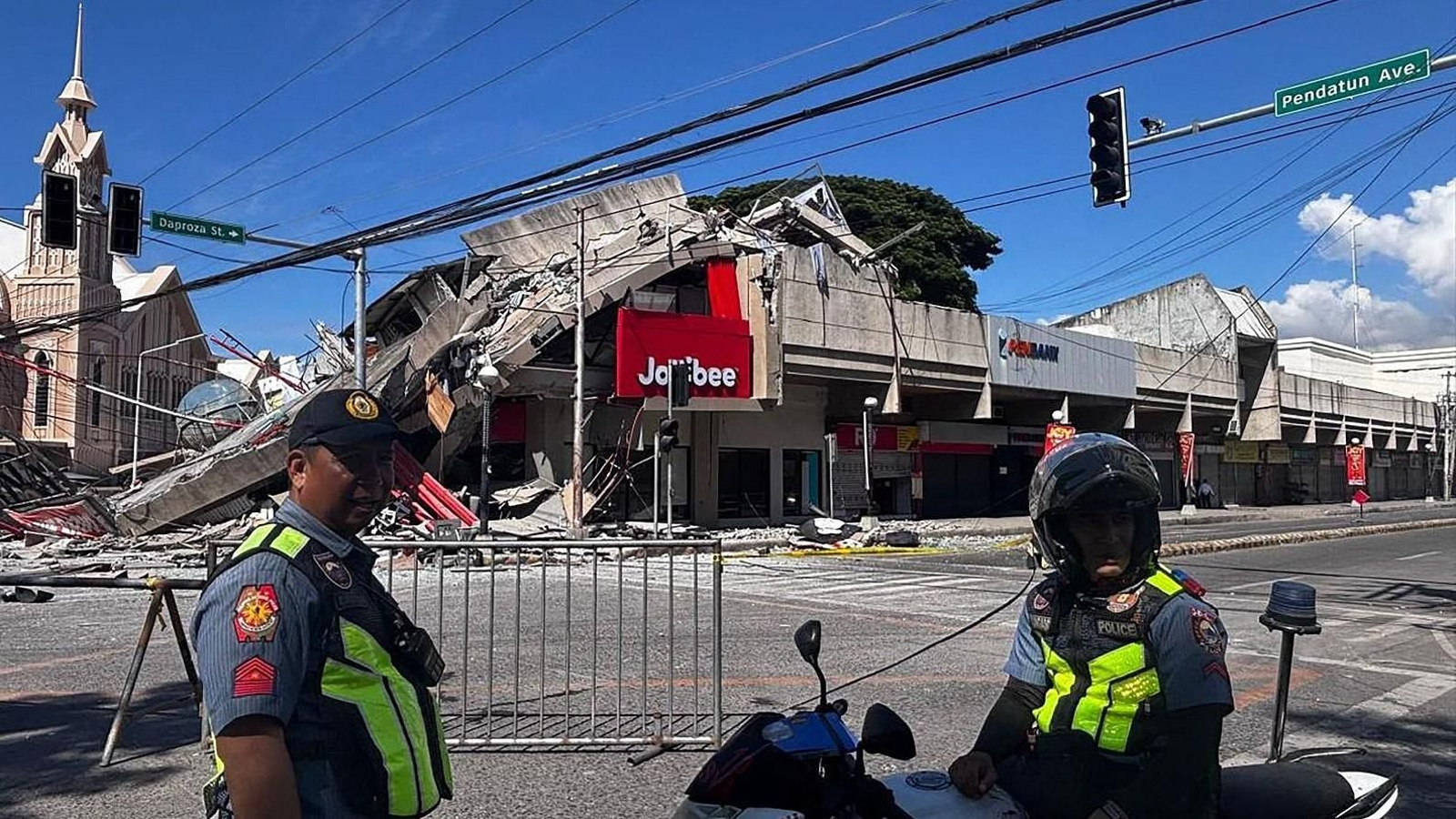 Policías se congregan frente a un restaurante de comida rápida derrumbado tras el terremoto en la ciudad de General Santos.