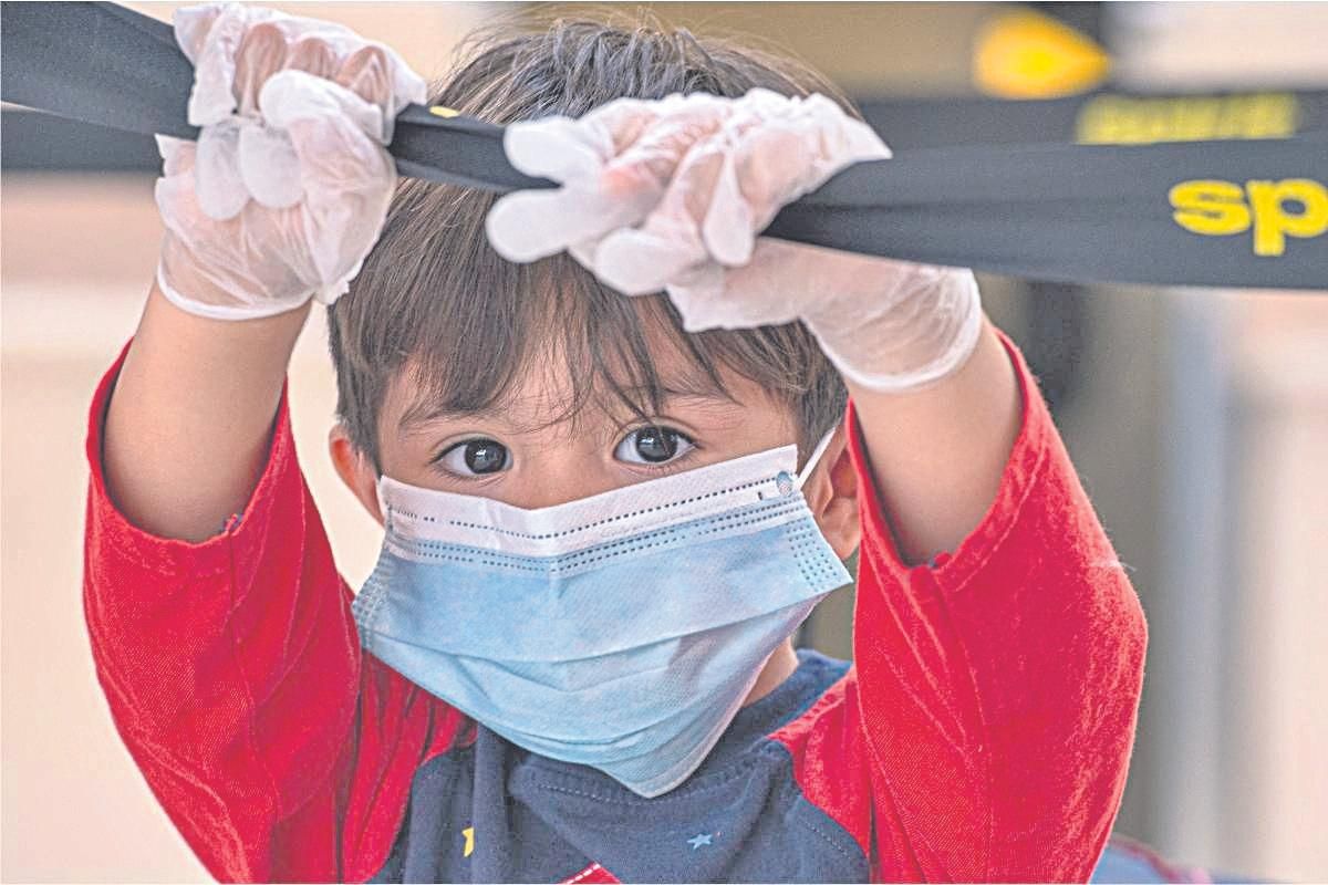 Un niño con guantes y mascarilla juega en una sala de recreo de un hospital.